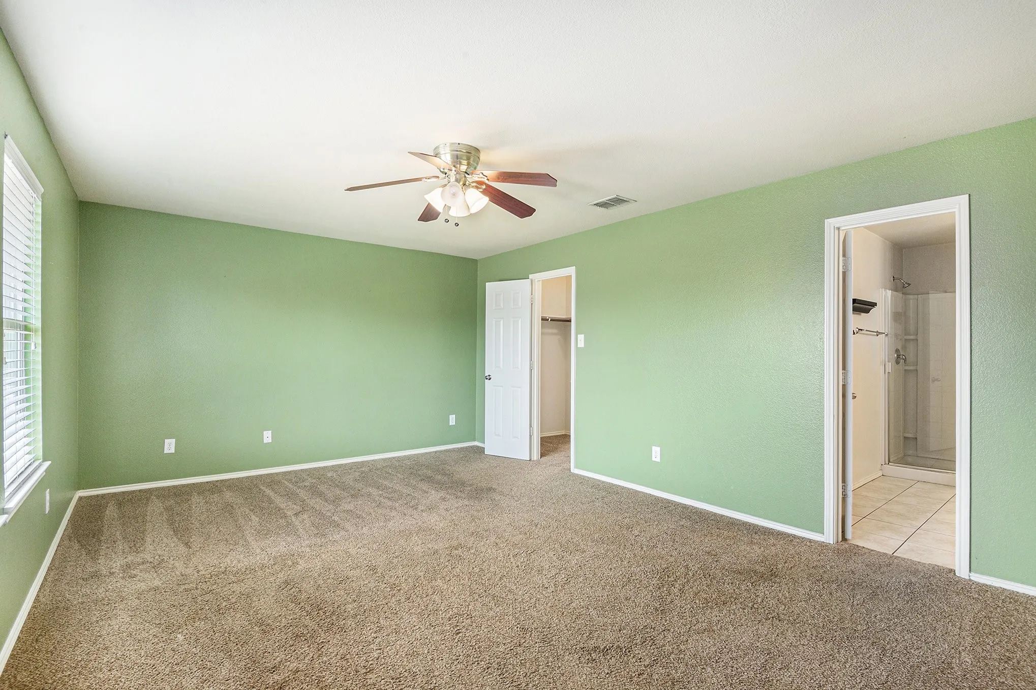Unfurnished bedroom with a walk in closet, carpet flooring, ceiling fan, and connected bathroom