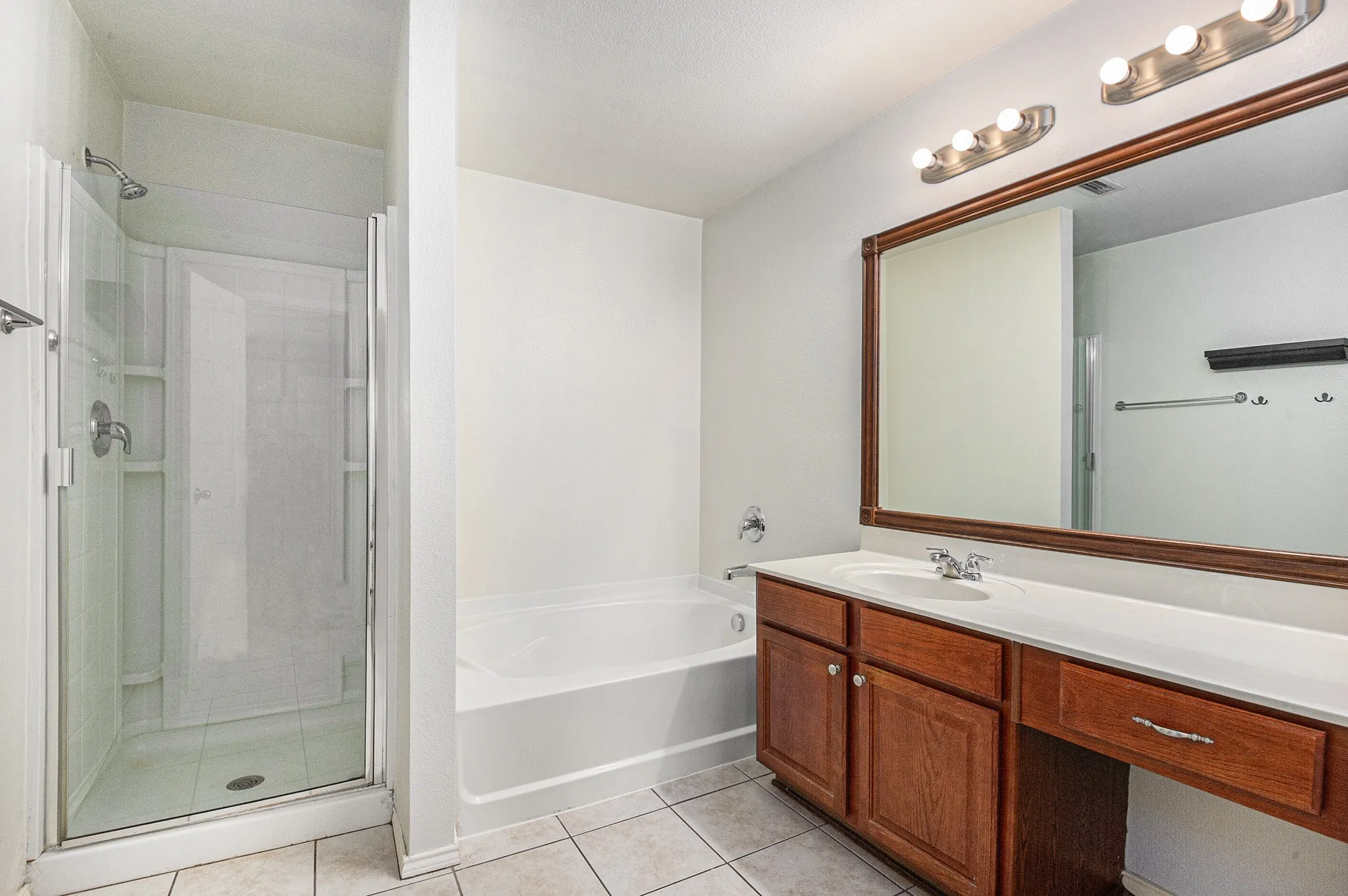 Bathroom featuring a bath, light tile patterned flooring, a stall shower, and vanity
