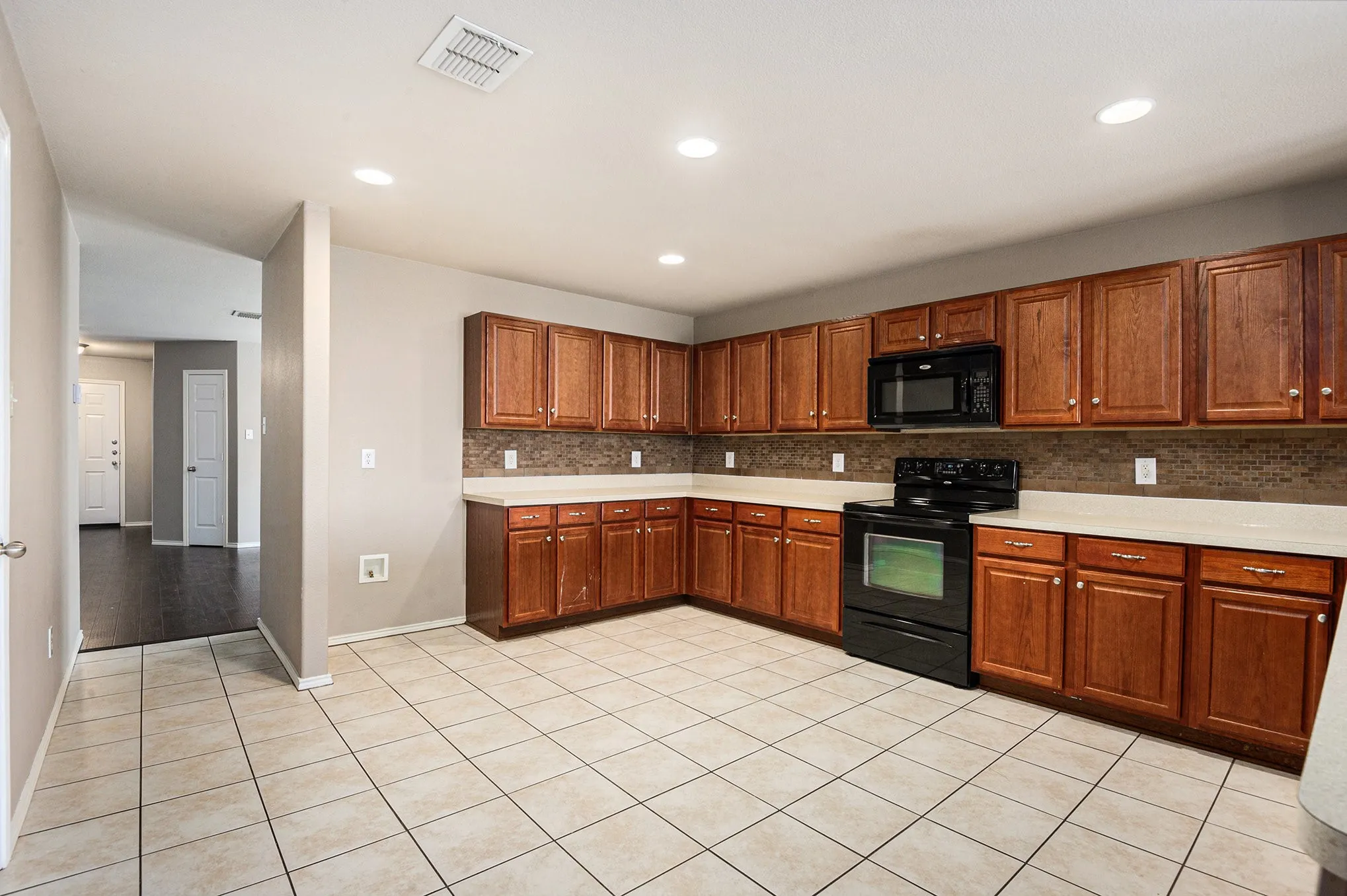 Kitchen featuring black appliances, tasteful backsplash, light countertops, light tile patterned flooring, and recessed lighting