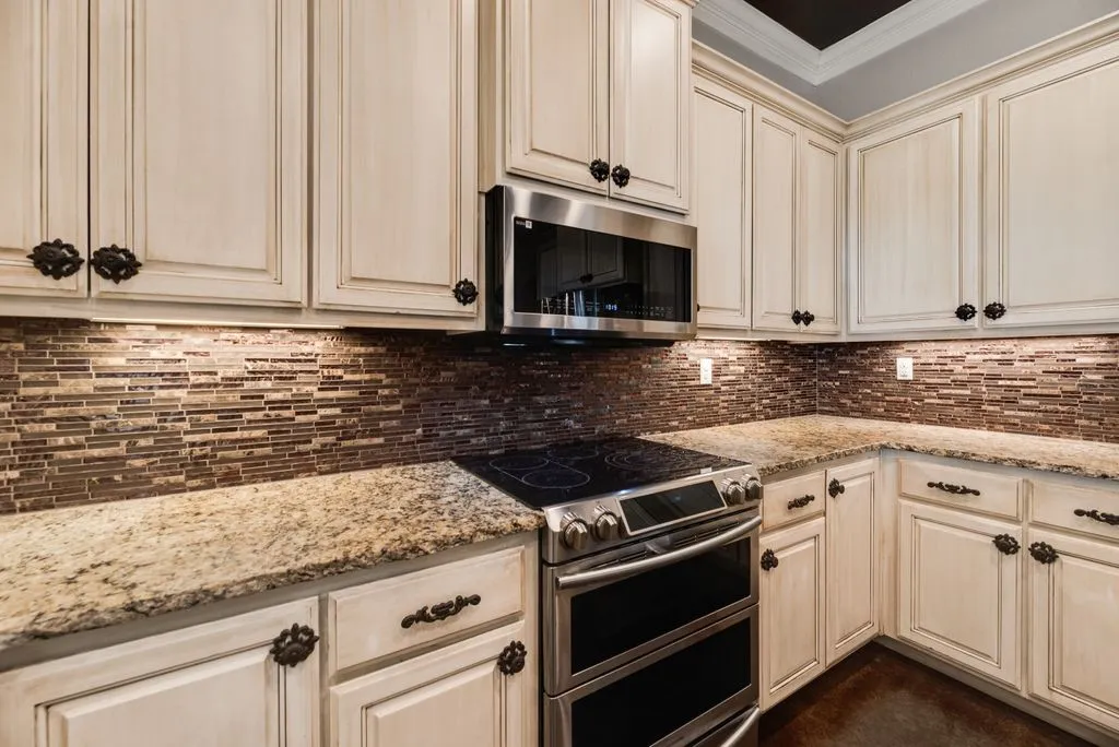 Recessed lighting highlights the tile backsplash, complemented by granite countertops and custom cabinetry