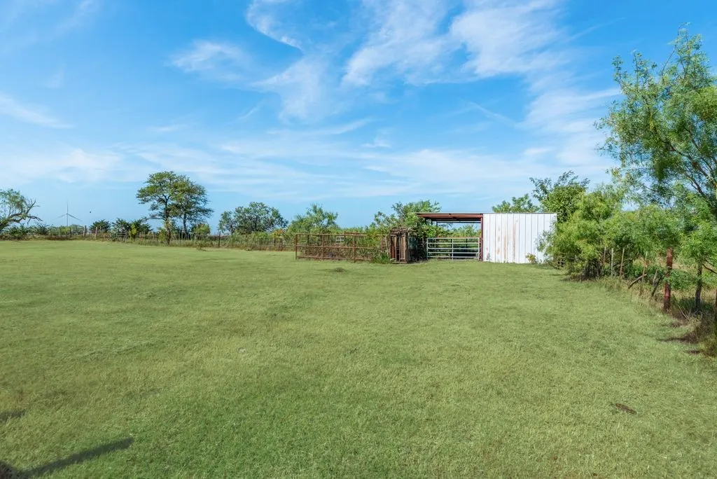 Expansive green space featuring a white-sided structure and perimeter fencing