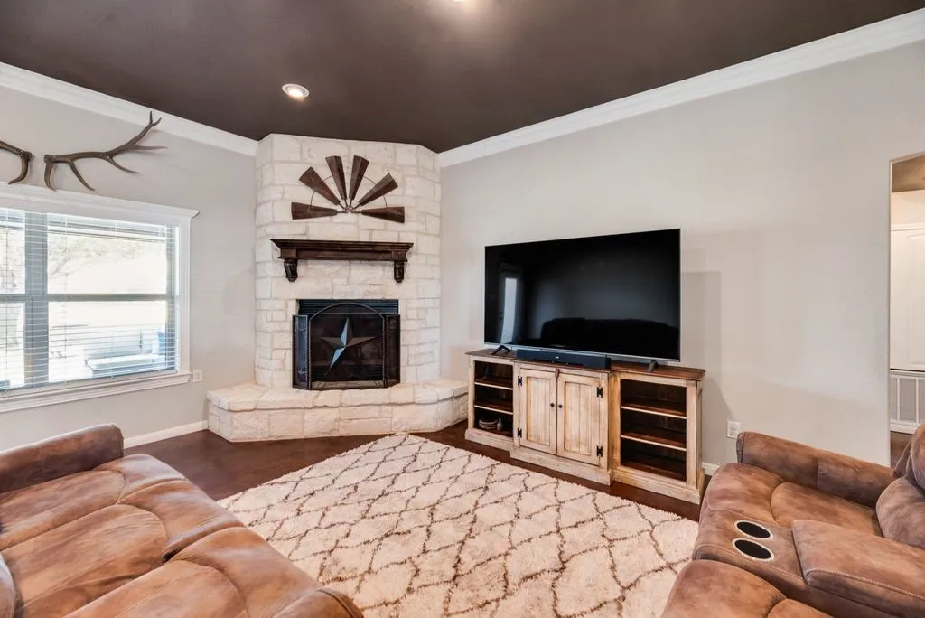 Corner fireplace with stone surround, wood mantel, and hearth