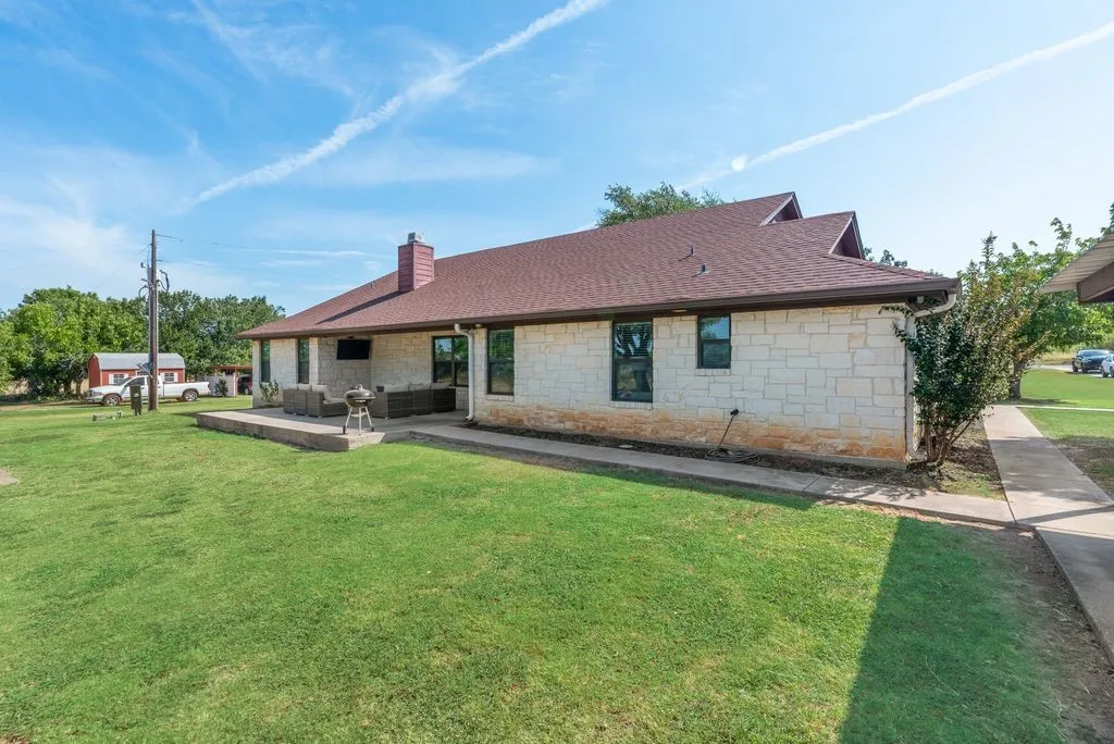 Stone exterior with a brown shingle roof, featuring multiple gables and a covered patio area