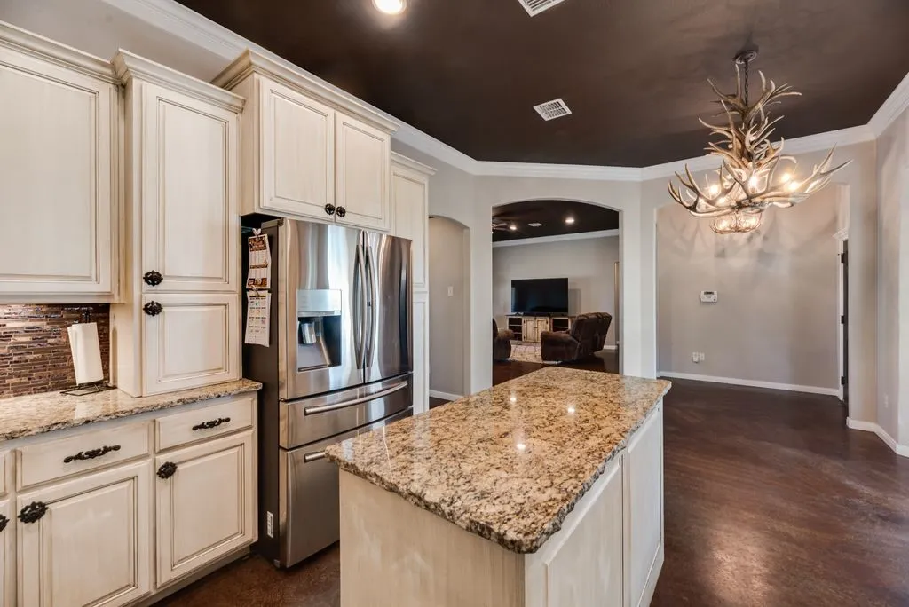 Kitchen featuring cream-colored cabinetry, granite countertops, and a mosaic tile backsplash