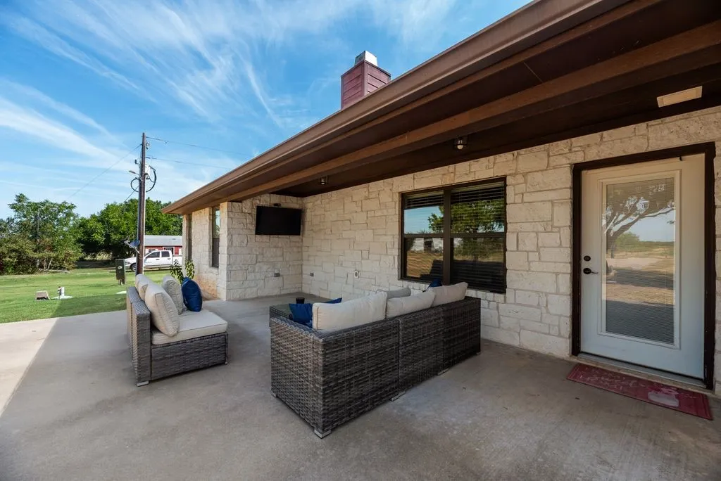 Covered patio with a concrete surface, stone exterior, and an exterior door with glass insert