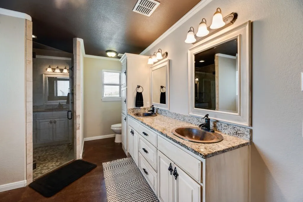Double vanity with granite countertops, integrated copper sinks, and individual framed mirrors