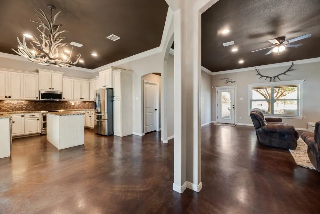 Open-concept living area with polished concrete flooring, recessed lighting, and a ceiling fan