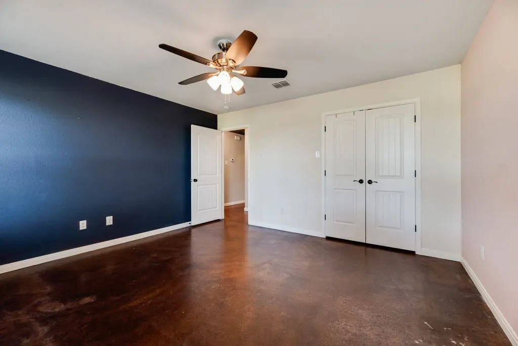 Polished concrete flooring, ceiling fan with integrated lighting, and multiple paneled doors