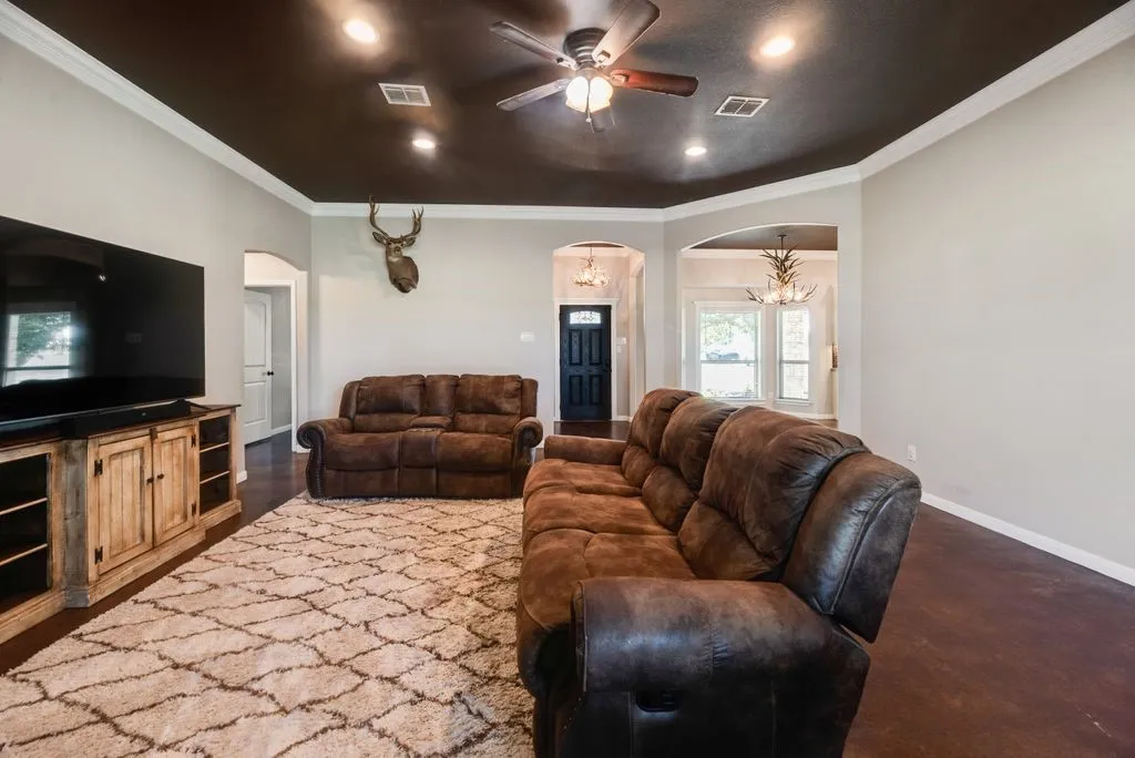 Living area with recessed lighting, ceiling fan, crown molding, and dark-stained flooring