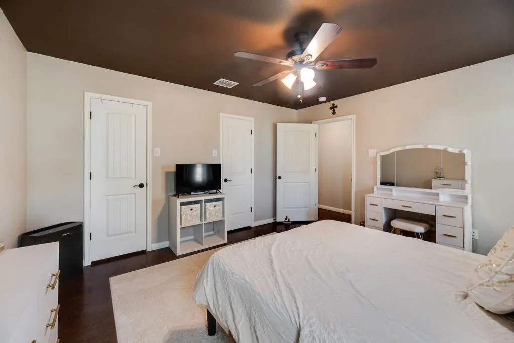 Dark-stained ceiling with a ceiling fan, light-toned walls, dark wood-finish flooring, and white paneled doors