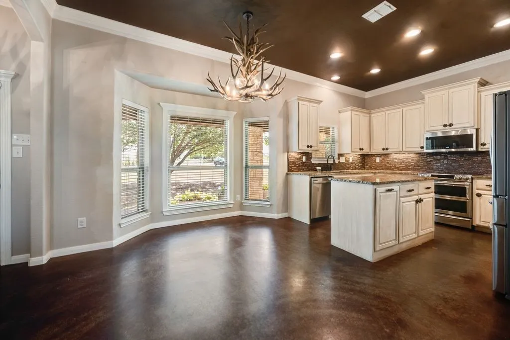 Elegant kitchen and dining area featuring white cabinetry with hardware accents, stainless steel appliances, and a center island with wood-finish countertops