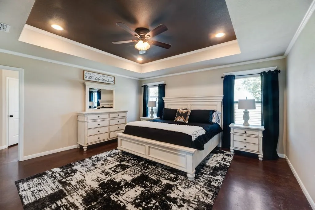 Tray ceiling with recessed lighting and a ceiling fan, dark wood-finish flooring, and white trim