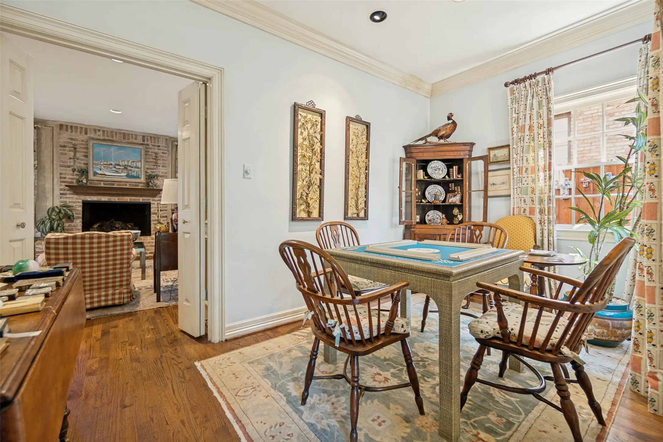 Hardwood flooring, crown molding, cased doorway, recessed lighting, and a brick fireplace