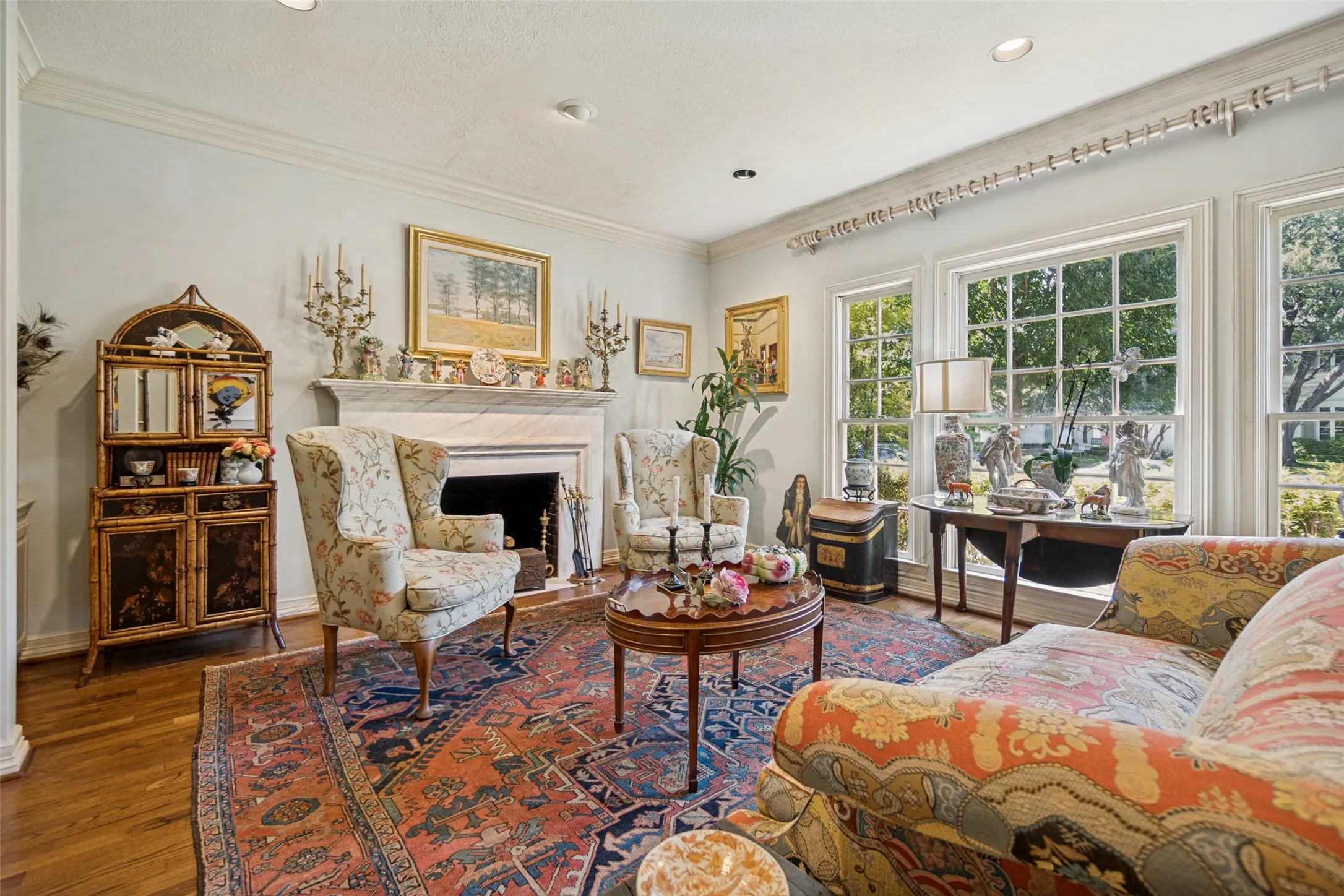 Hardwood flooring, crown molding, a white marble fireplace, recessed lighting, and multiple windows with grid patterns