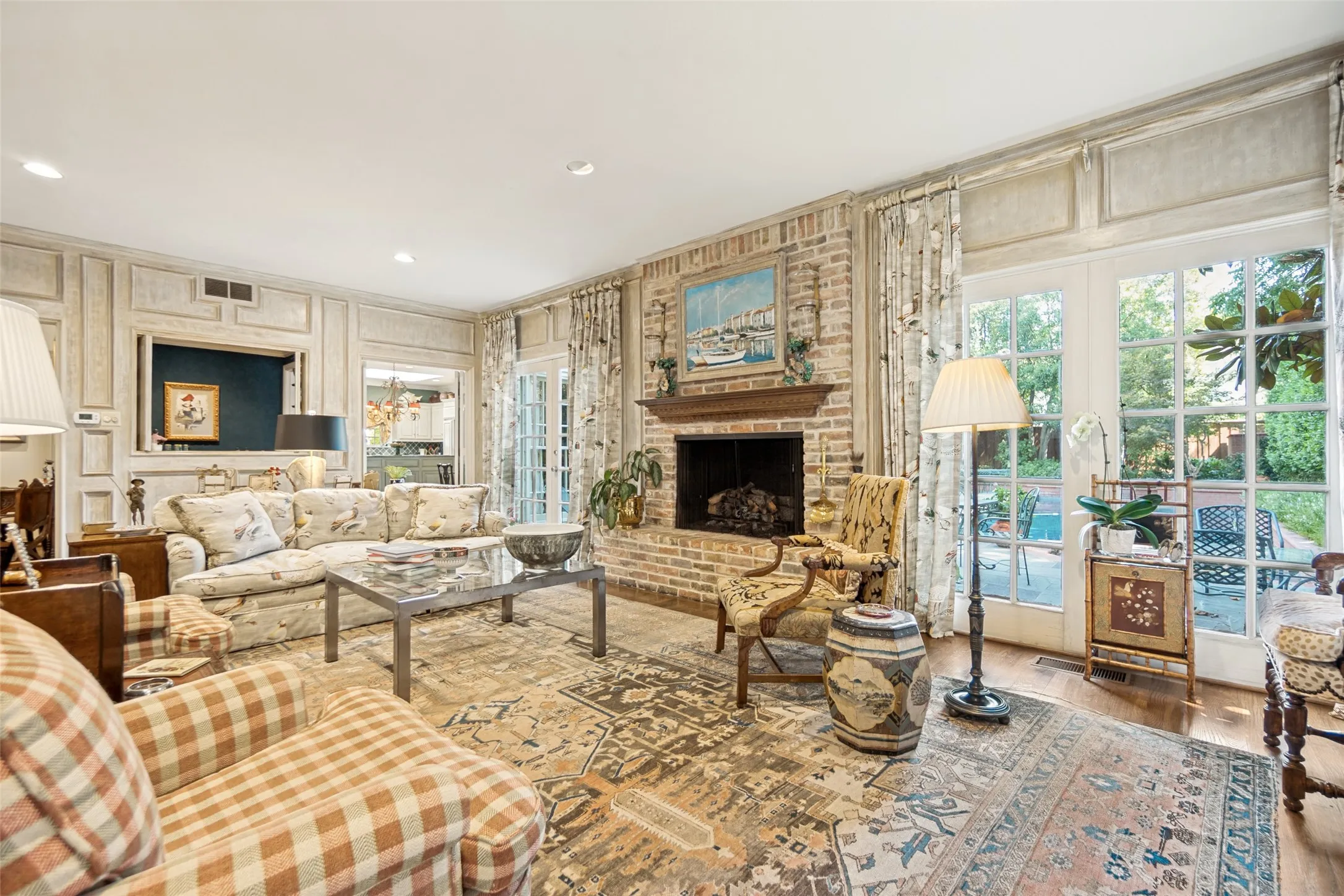 Brick fireplace with a wood mantel, paneled walls, and French doors