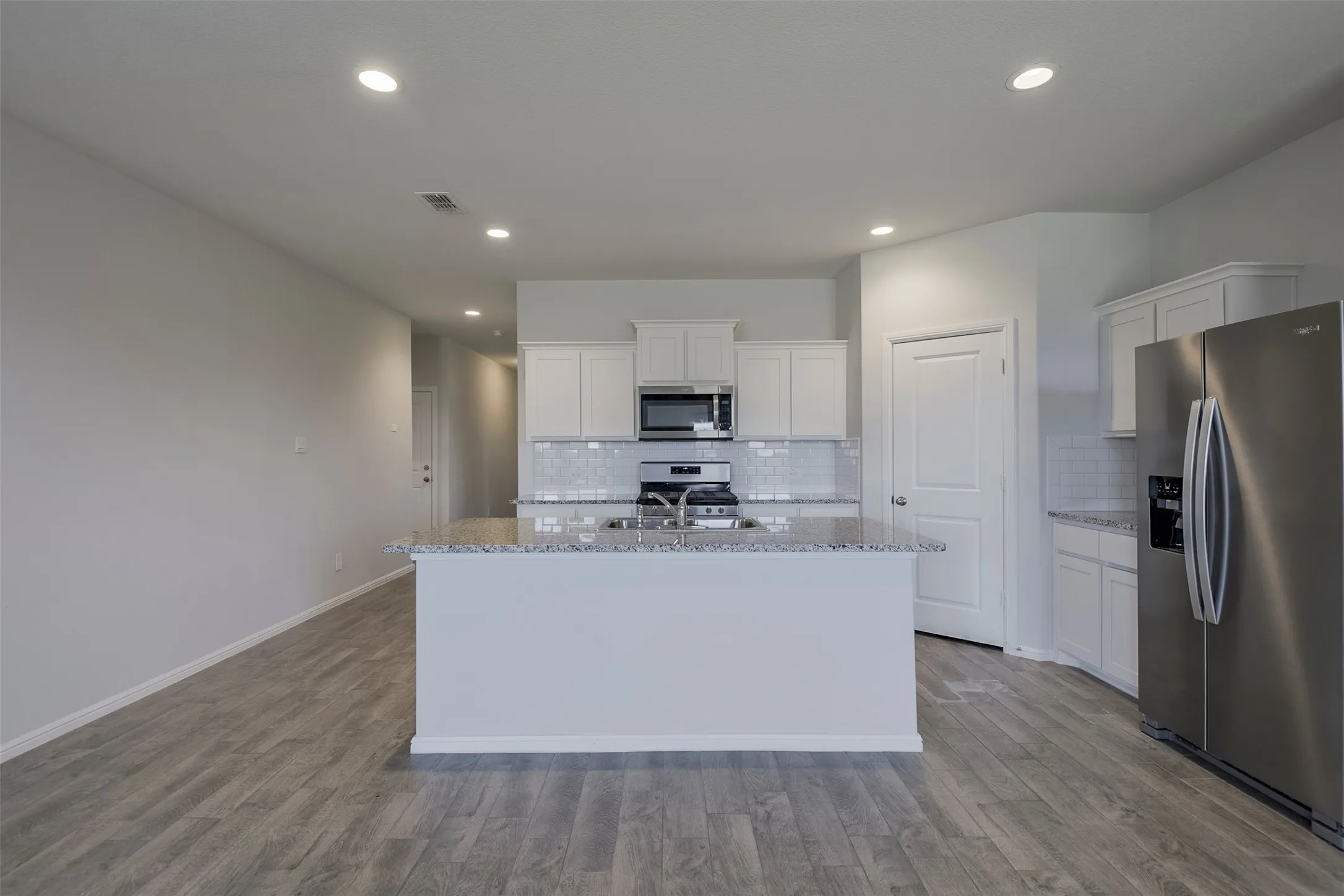 Kitchen featuring an island with a light-colored countertop, white cabinetry, a built-in microwave, and stainless steel appliances