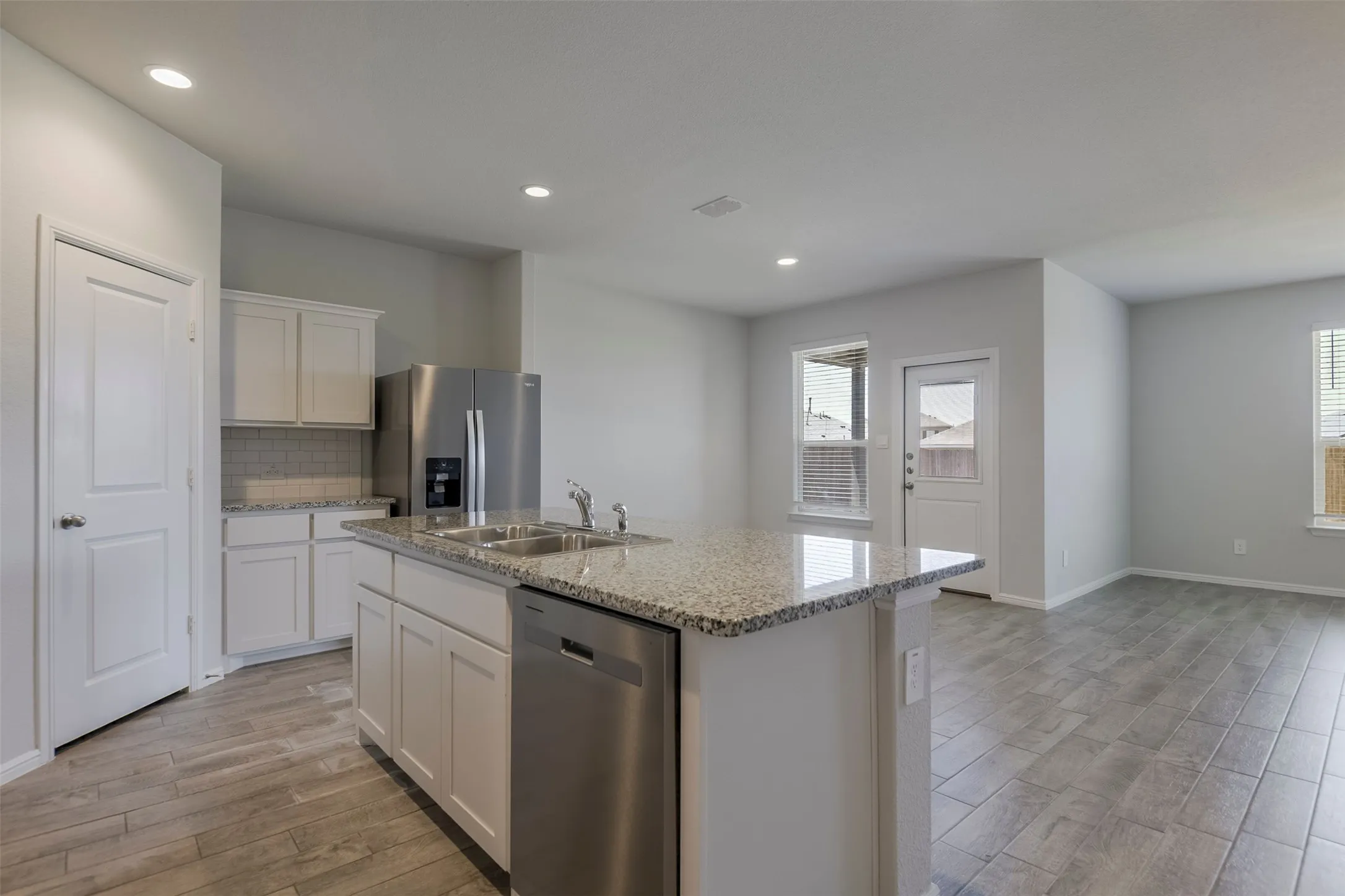 Kitchen with white cabinetry, granite countertops, tile backsplash, and stainless steel appliances