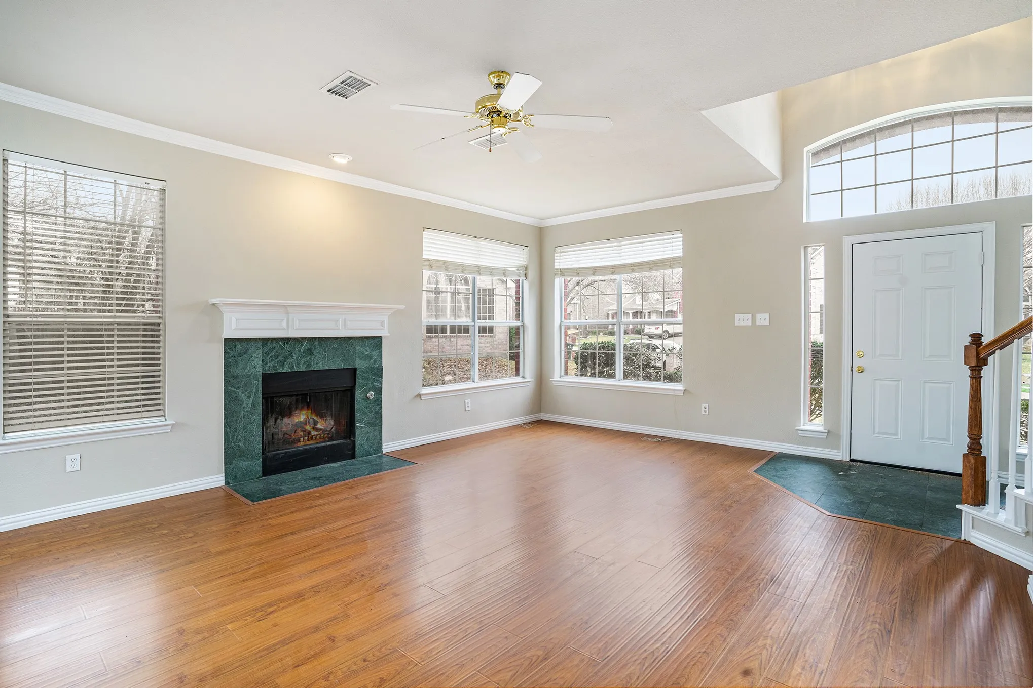 Foyer featuring wood-type flooring, ornamental molding, ceiling fan, and a fireplace