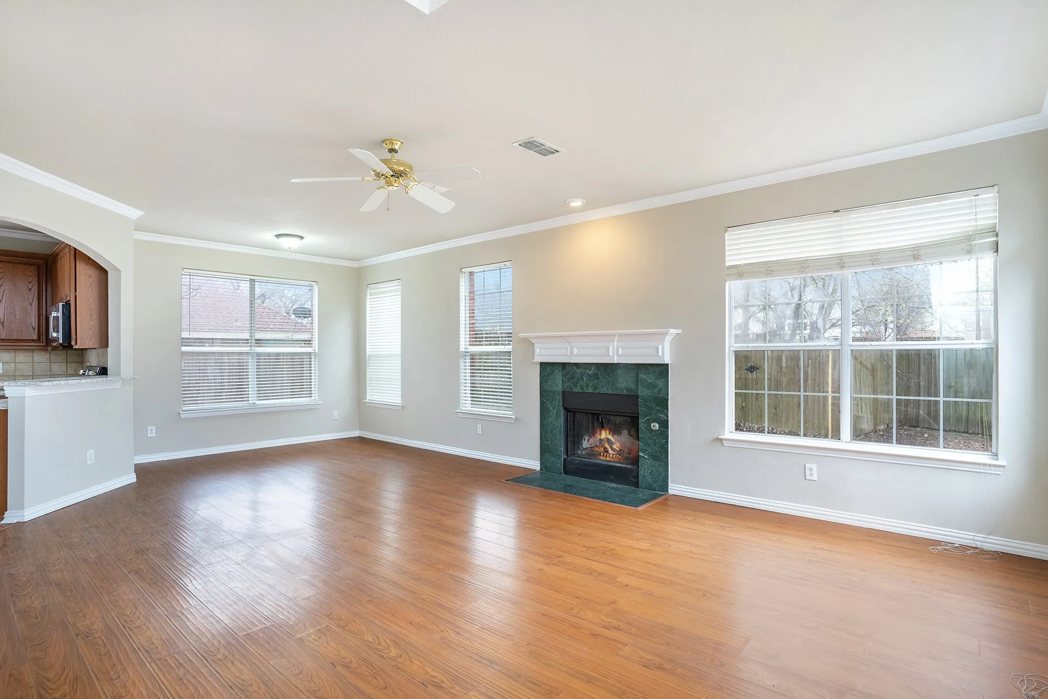 Unfurnished living room featuring a healthy amount of sunlight, crown molding, a tile fireplace, and wood-type flooring