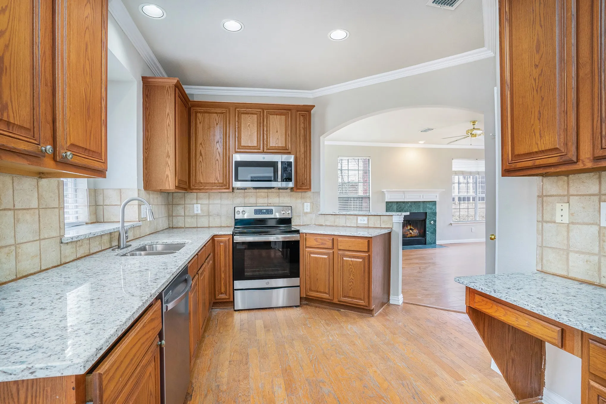 Kitchen with backsplash, appliances with stainless steel finishes, sink, and light wood-type flooring