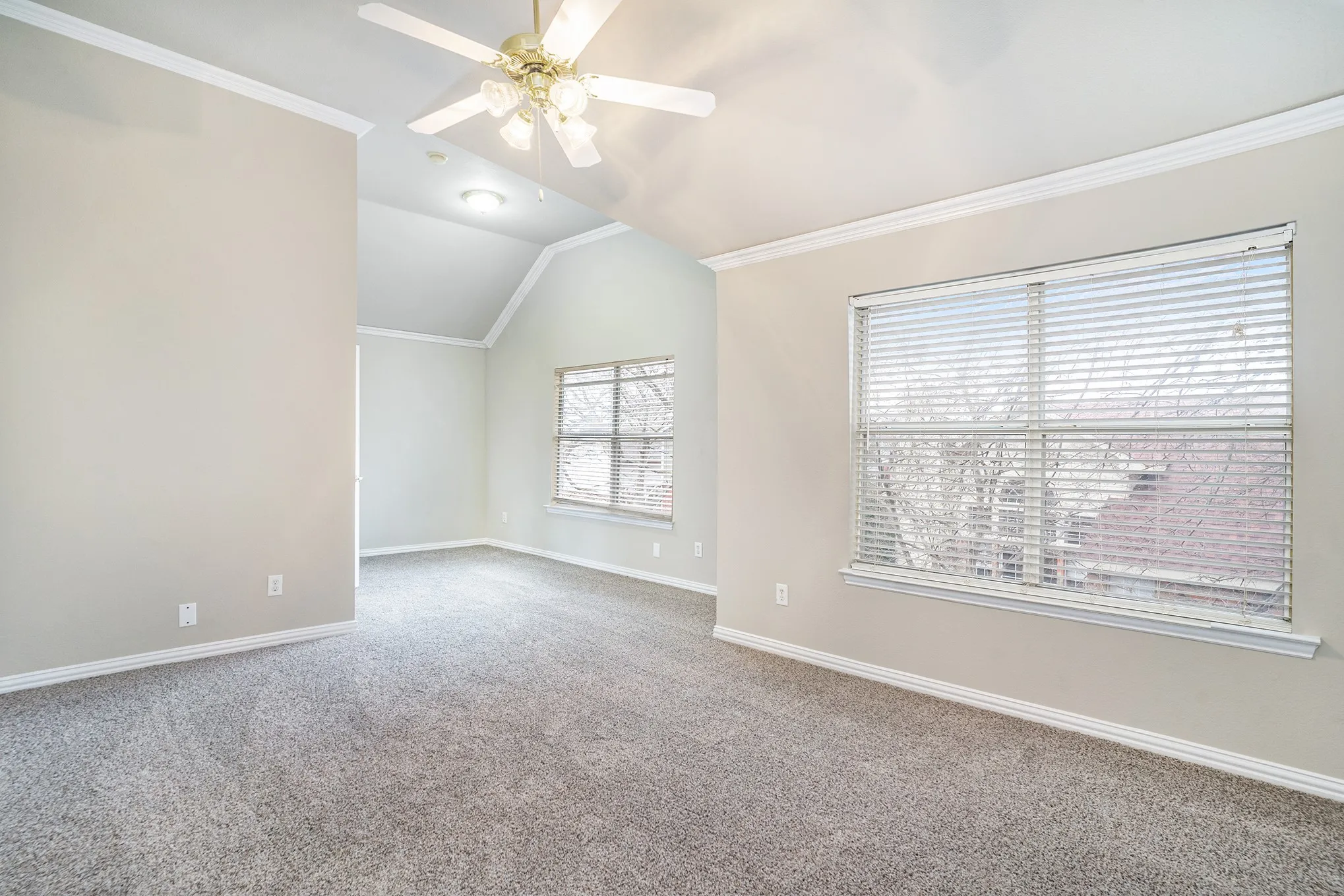 Spare room featuring ceiling fan, ornamental molding, carpet floors, and lofted ceiling