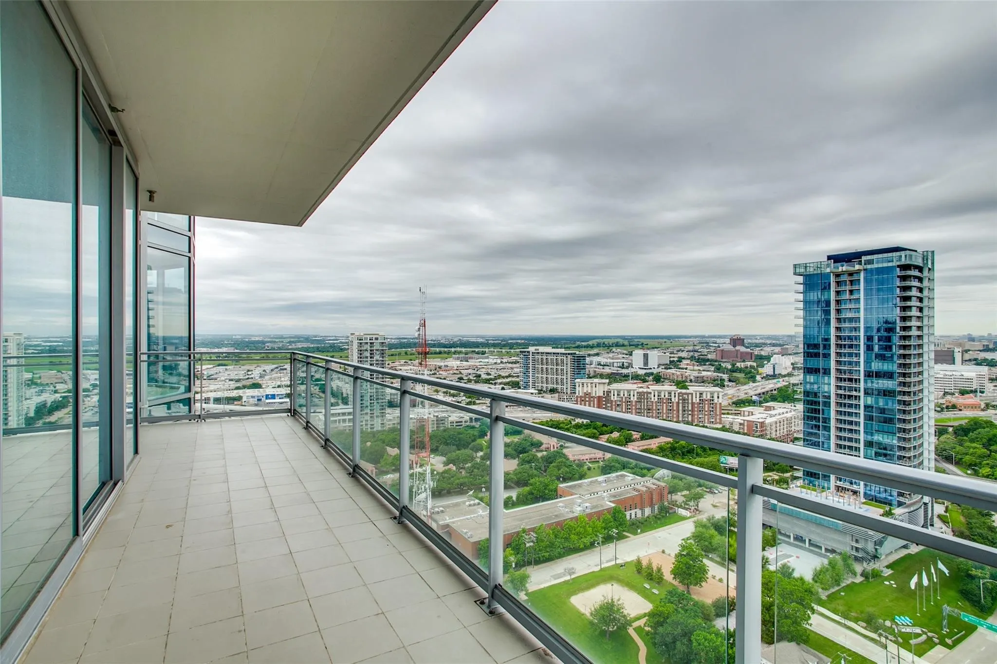 Spacious balcony featuring tile flooring and a glass railing system
