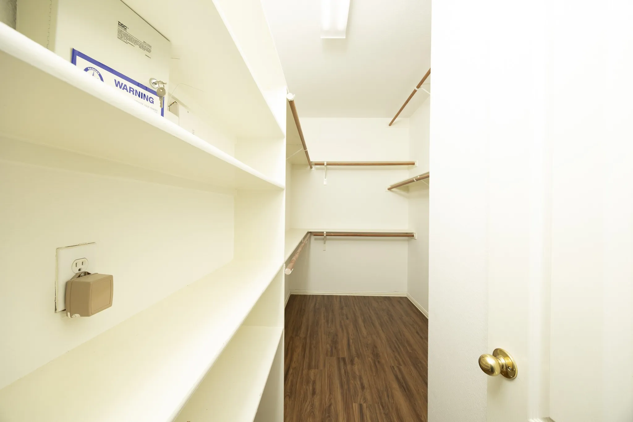 Walk in closet with dark wood-style floors