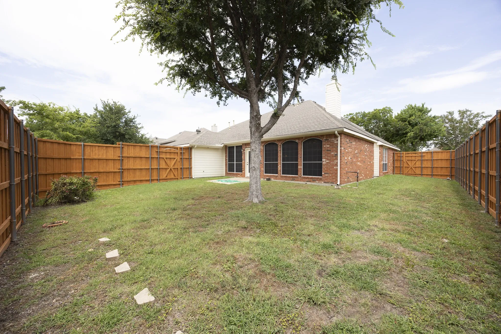 Rear view of house with brick siding, a fenced backyard, and a chimney