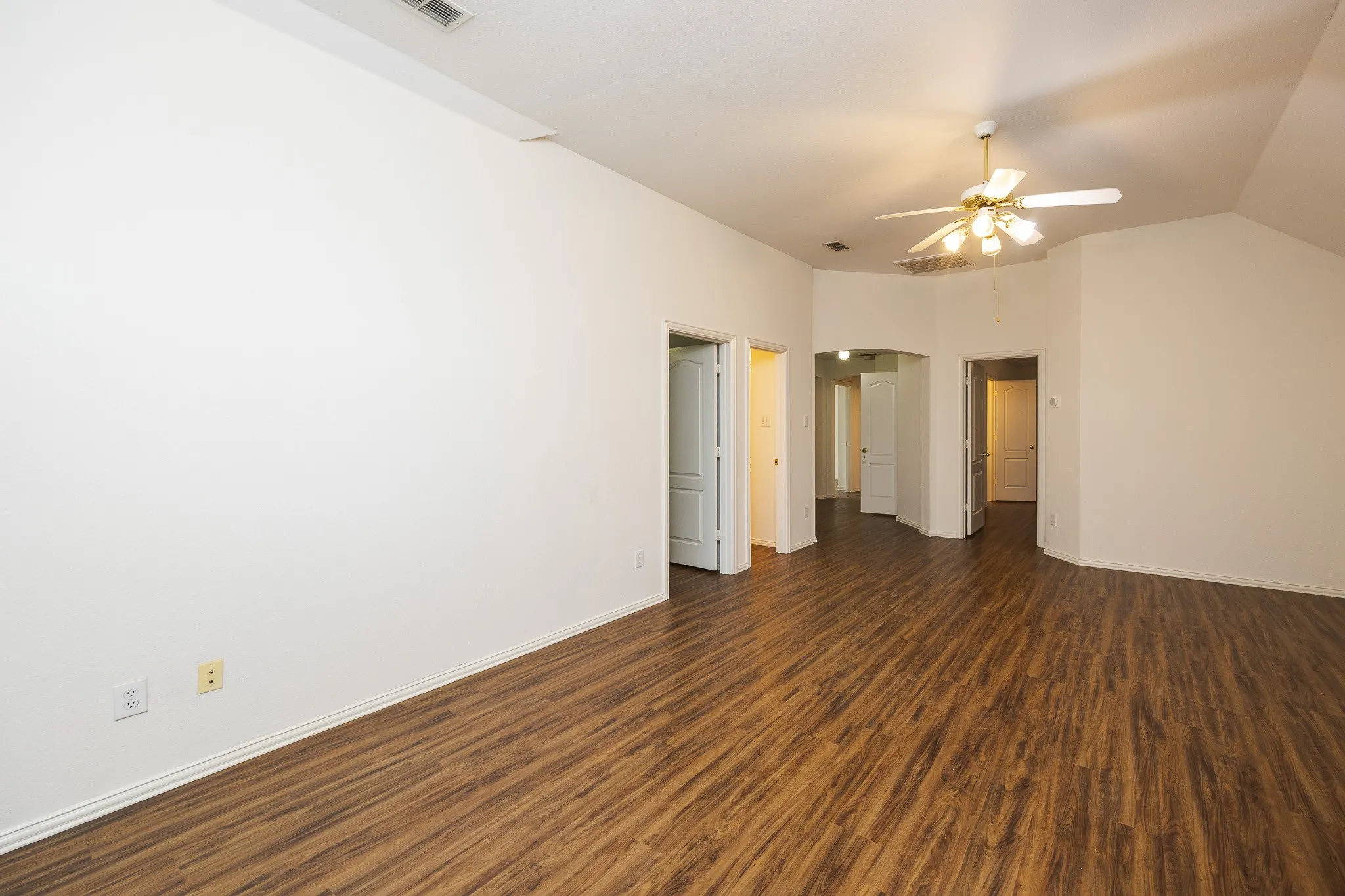 Spare room featuring dark wood finished floors, a ceiling fan, and lofted ceiling