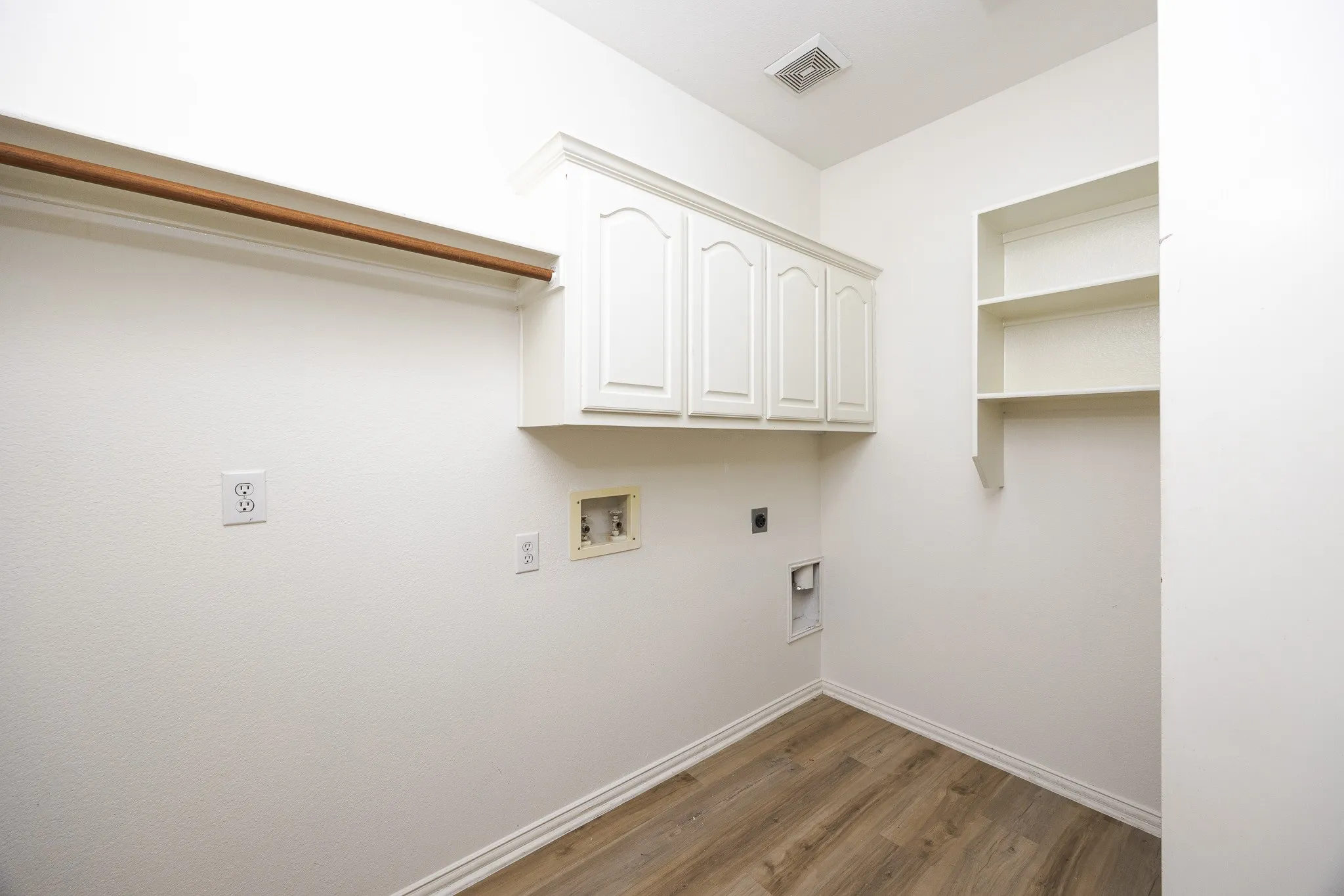 Laundry area featuring hookup for an electric dryer, wood finished floors, cabinet space, and hookup for a washing machine