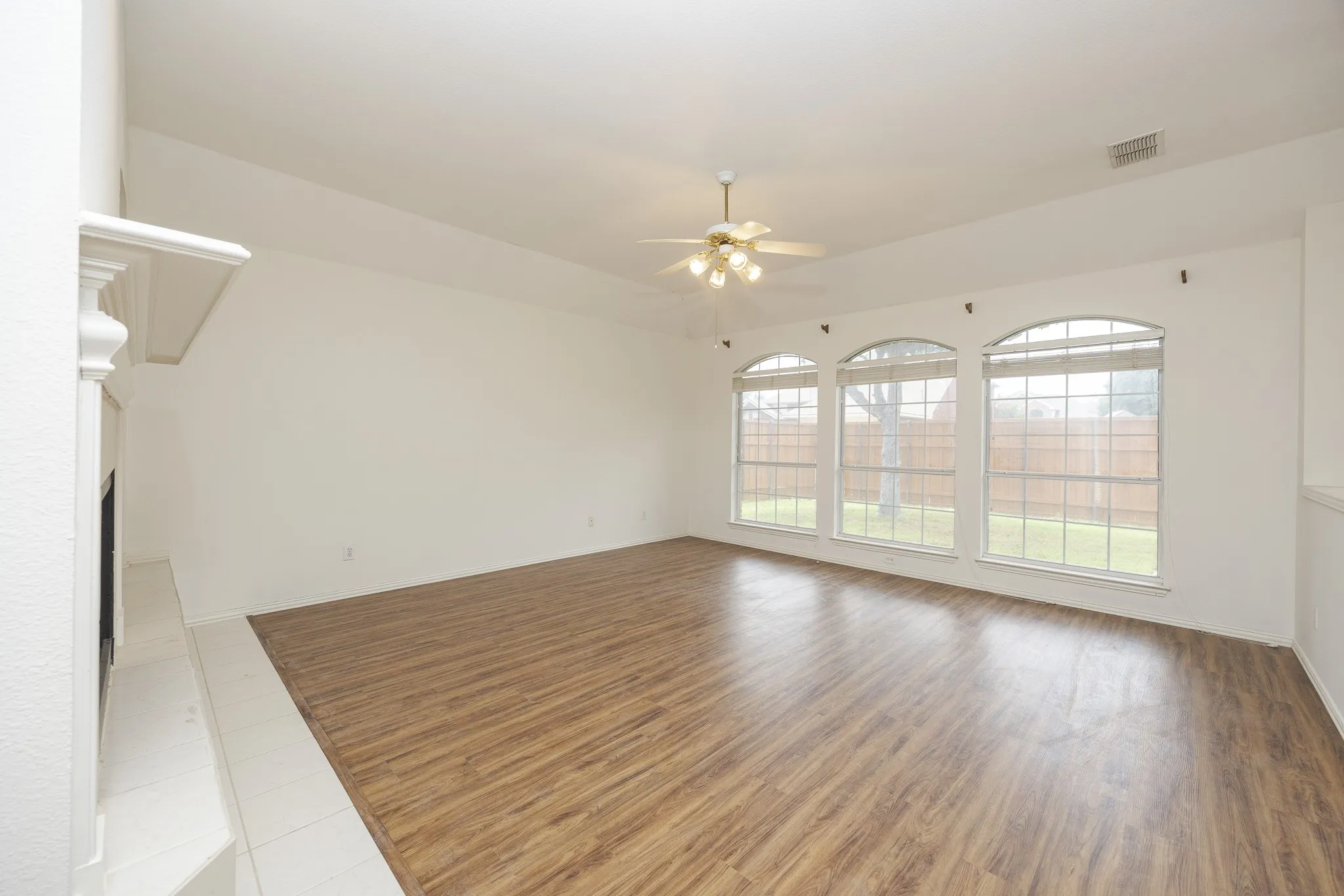 Unfurnished living room with a ceiling fan, wood finished floors, and a fireplace