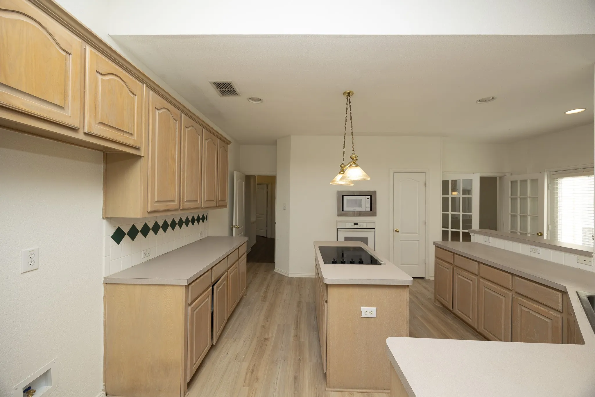 Kitchen featuring white appliances, a kitchen island, light brown cabinetry, light countertops, and light wood-type flooring
