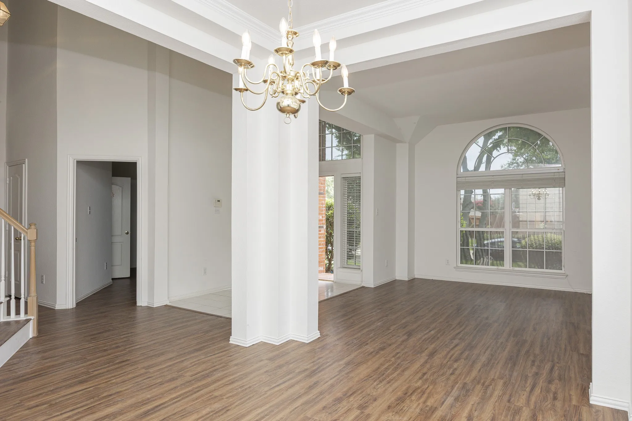 Spare room featuring a chandelier, wood finished floors, stairs, plenty of natural light, and crown molding