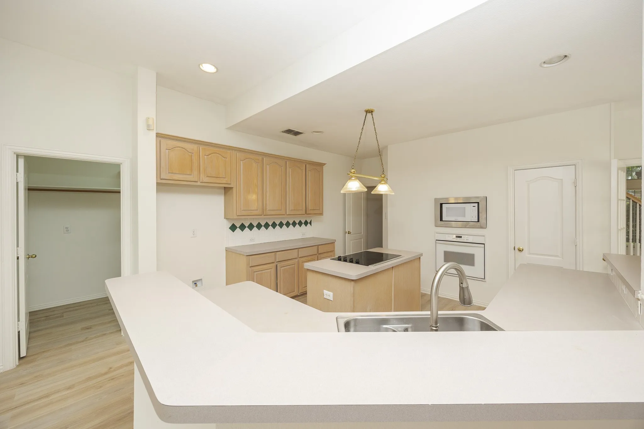 Kitchen with white appliances, a kitchen island, light brown cabinets, light wood-style floors, and recessed lighting