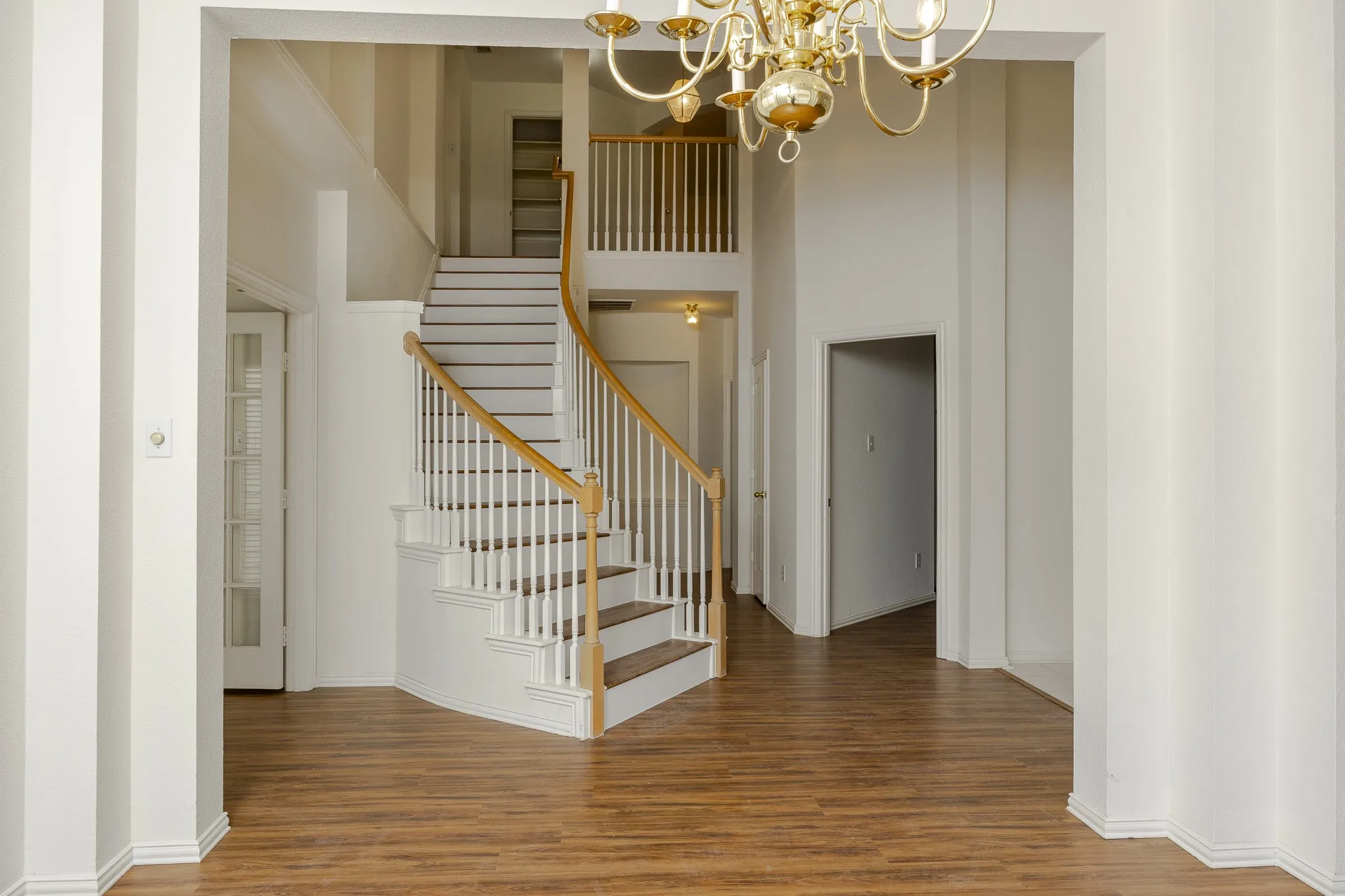 Stairway with a chandelier, wood finished floors, and a high​​‌​​​​‌​​‌‌​‌‌​​​‌‌​‌​‌​‌​​​‌​​ ceiling
