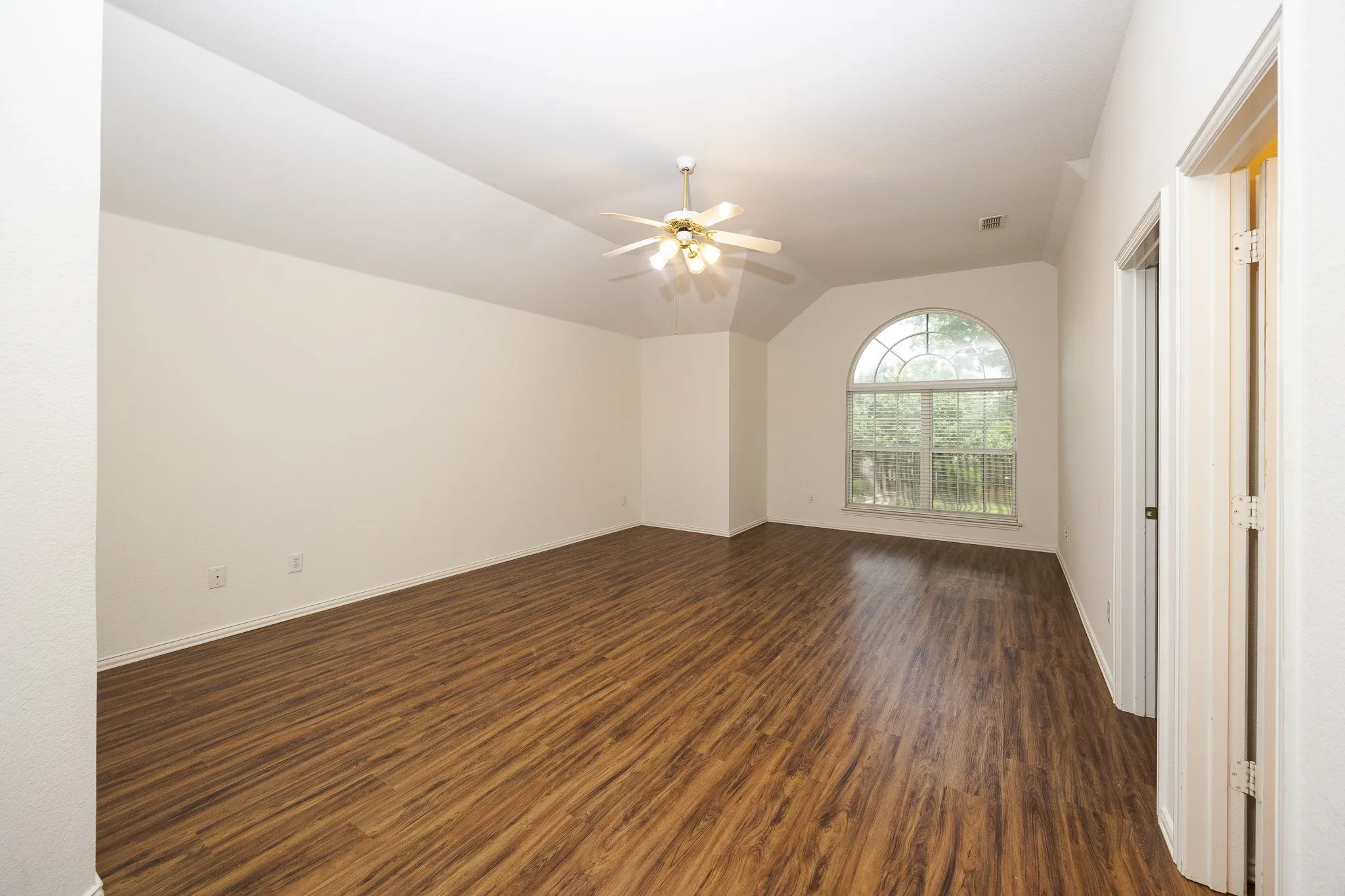 Spare room with dark wood-type flooring, ceiling fan, and vaulted ceiling