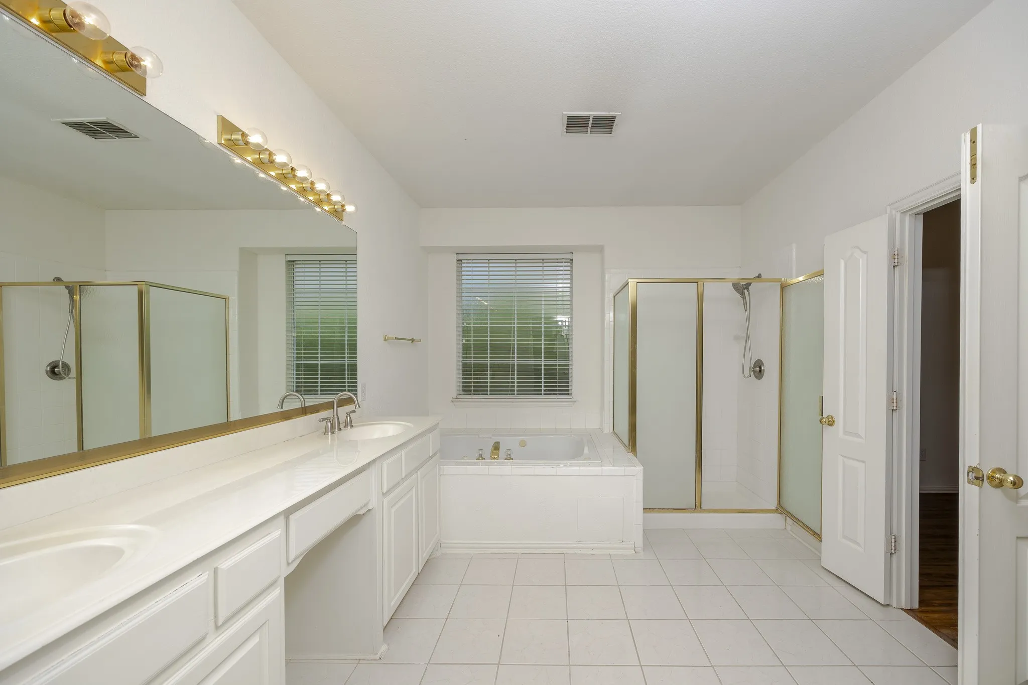 Bathroom with a shower stall, a garden tub, double vanity, and tile patterned floors