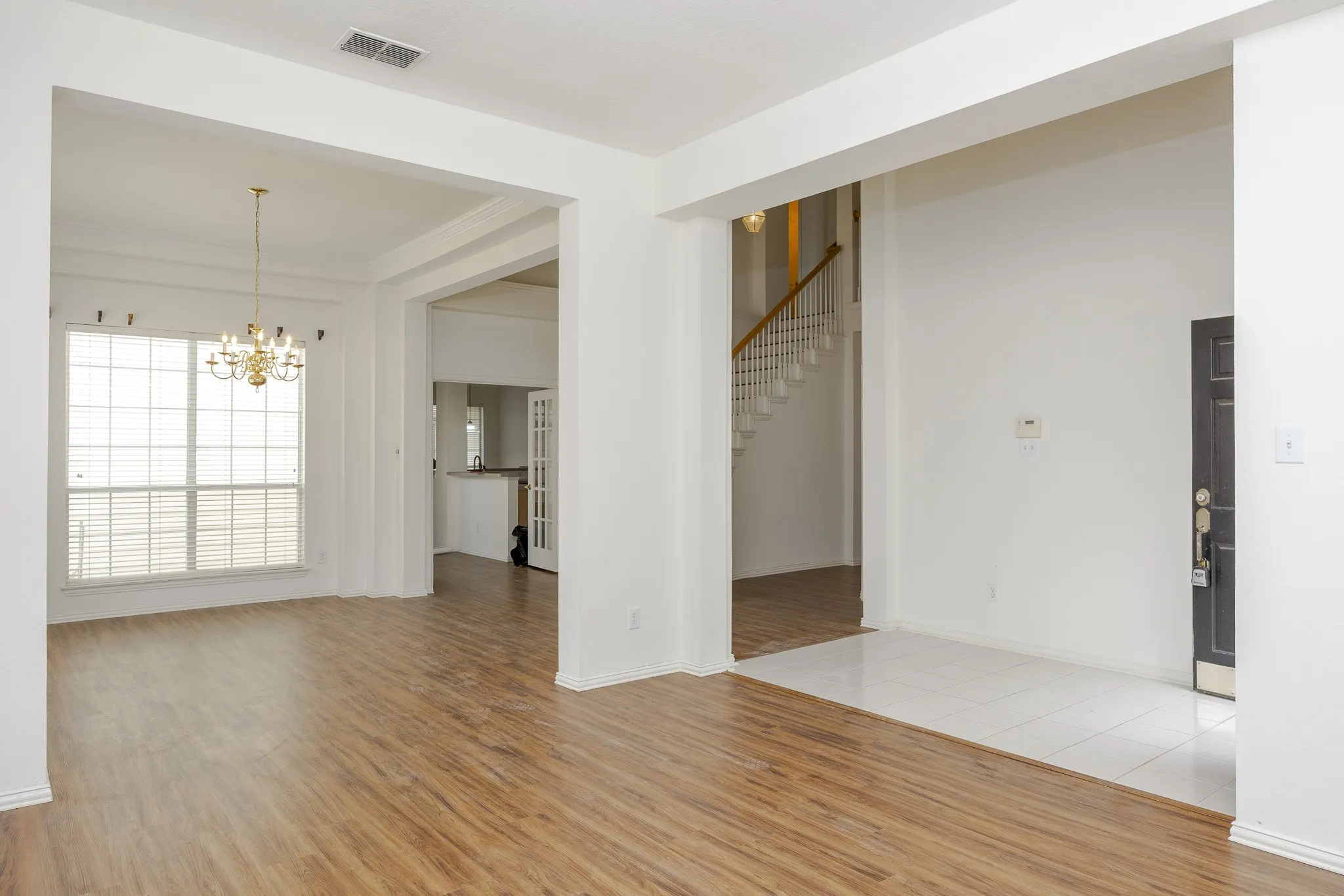 Unfurnished room featuring light wood-style flooring, a chandelier, stairway, and ornamental molding
