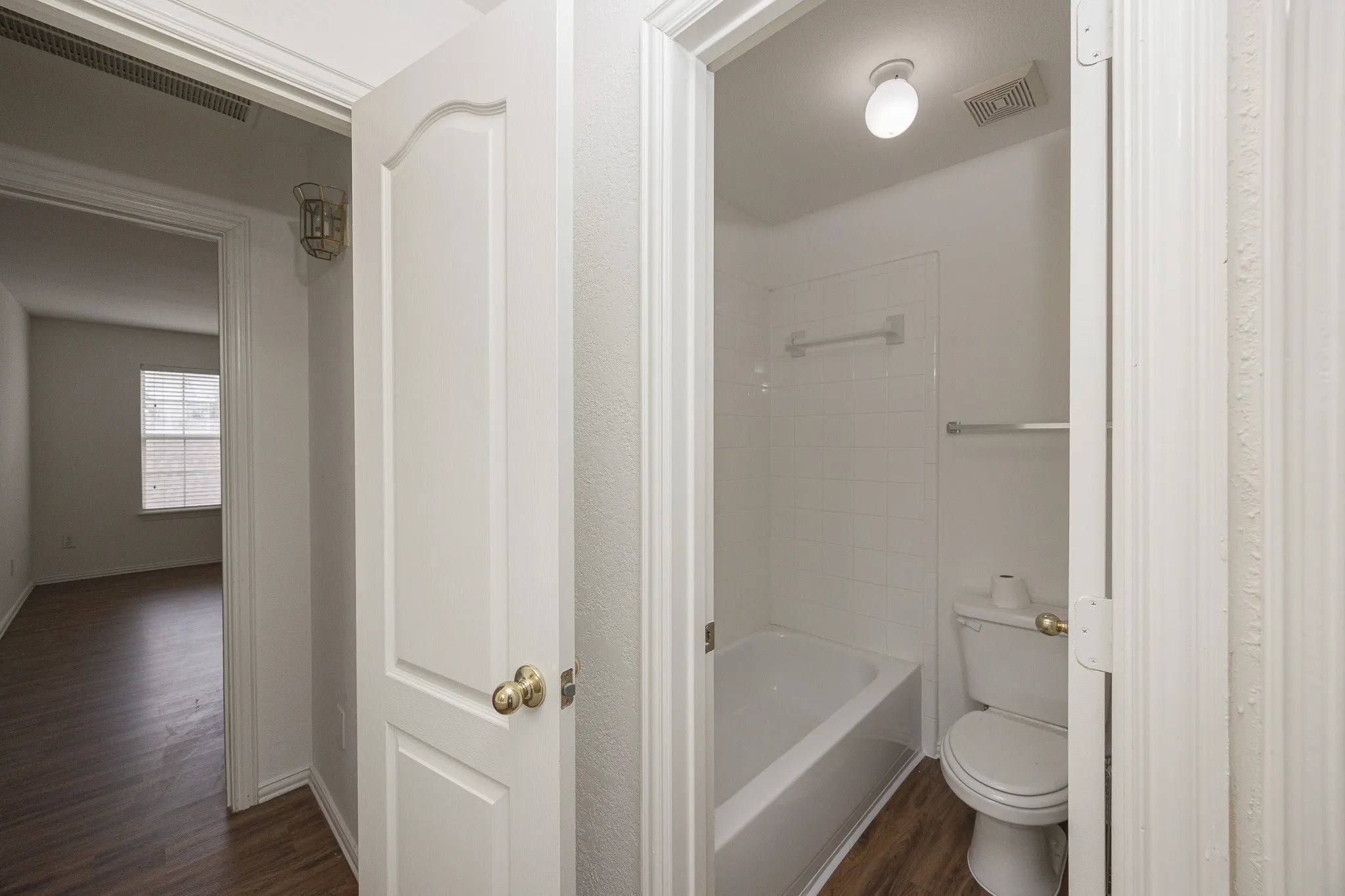 Full bathroom featuring wood finished floors and washtub / shower combination