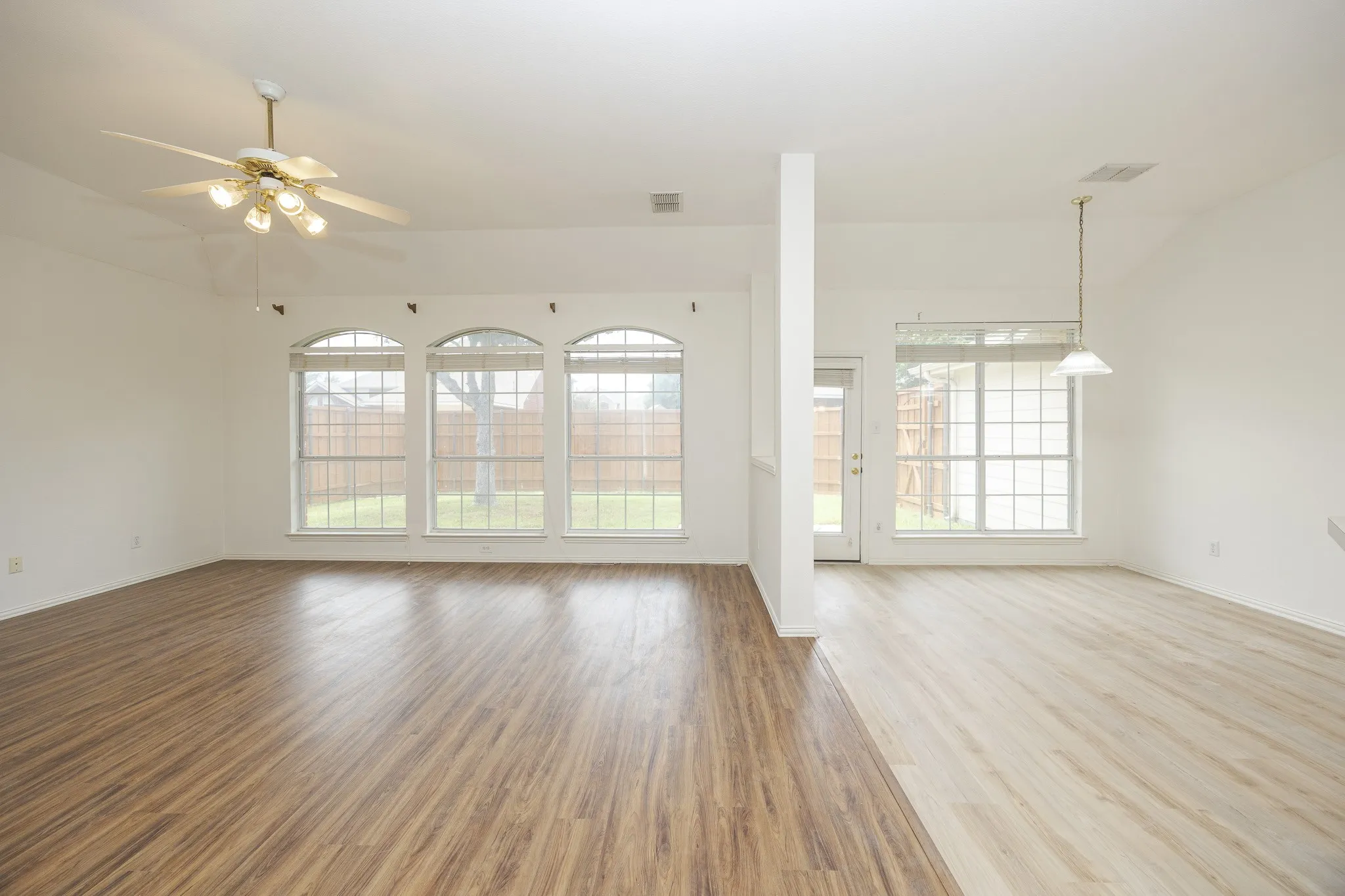 Unfurnished living room with vaulted ceiling, healthy amount of natural light, a ceiling fan, and wood finished floors
