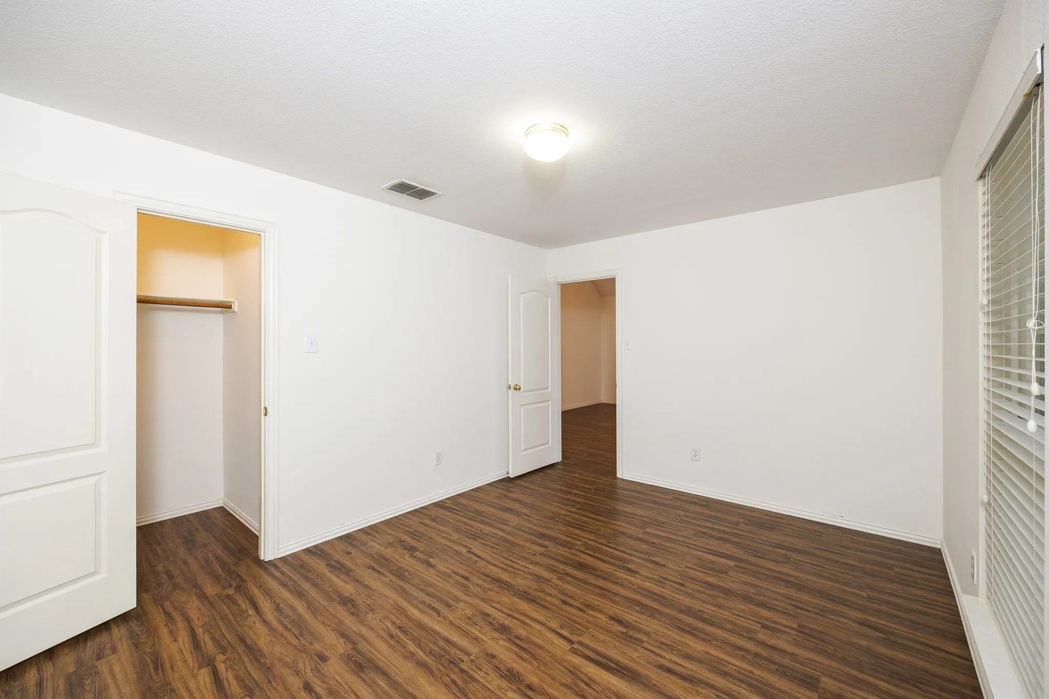 Unfurnished bedroom with dark wood-style flooring, a closet, and a spacious closet