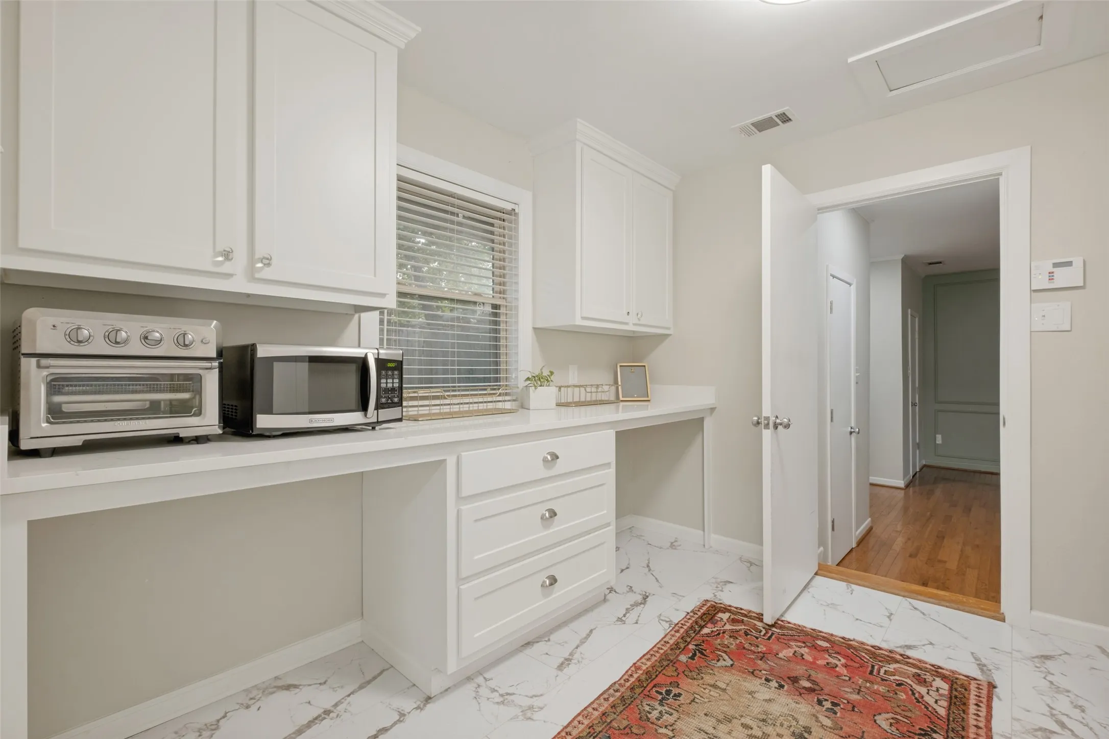 Oversized Laundry and Utility Room located between kitchen and Primary Suite. Large quartz top area perfect for two desks or crafting with built in drawer and cabinets above laundry area to the left.  Full size W/D space.