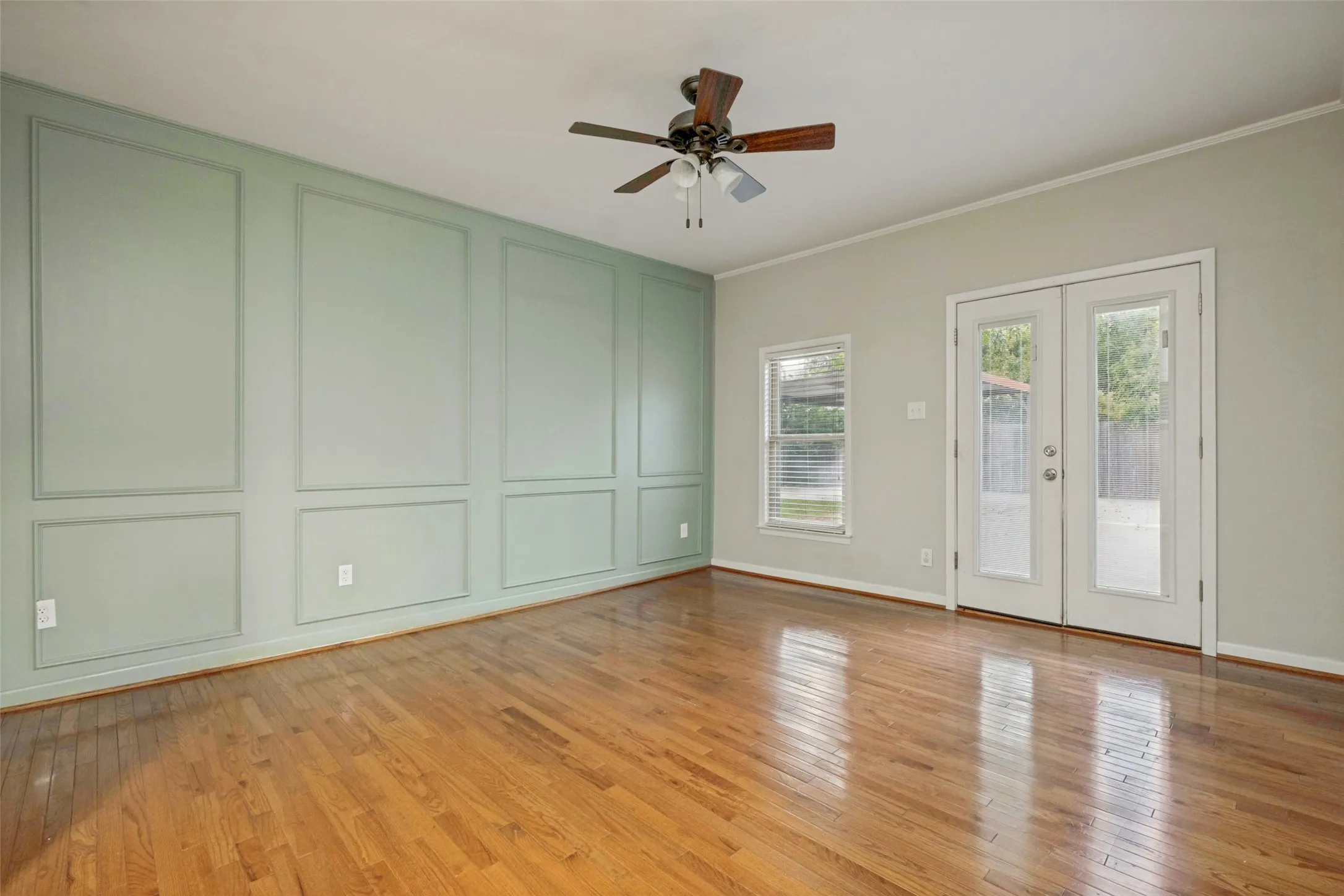 Beautiful Primary Bedroom located in its own wing with stunning paint and trimmed wall with double french doors that open up to the back courtyard.