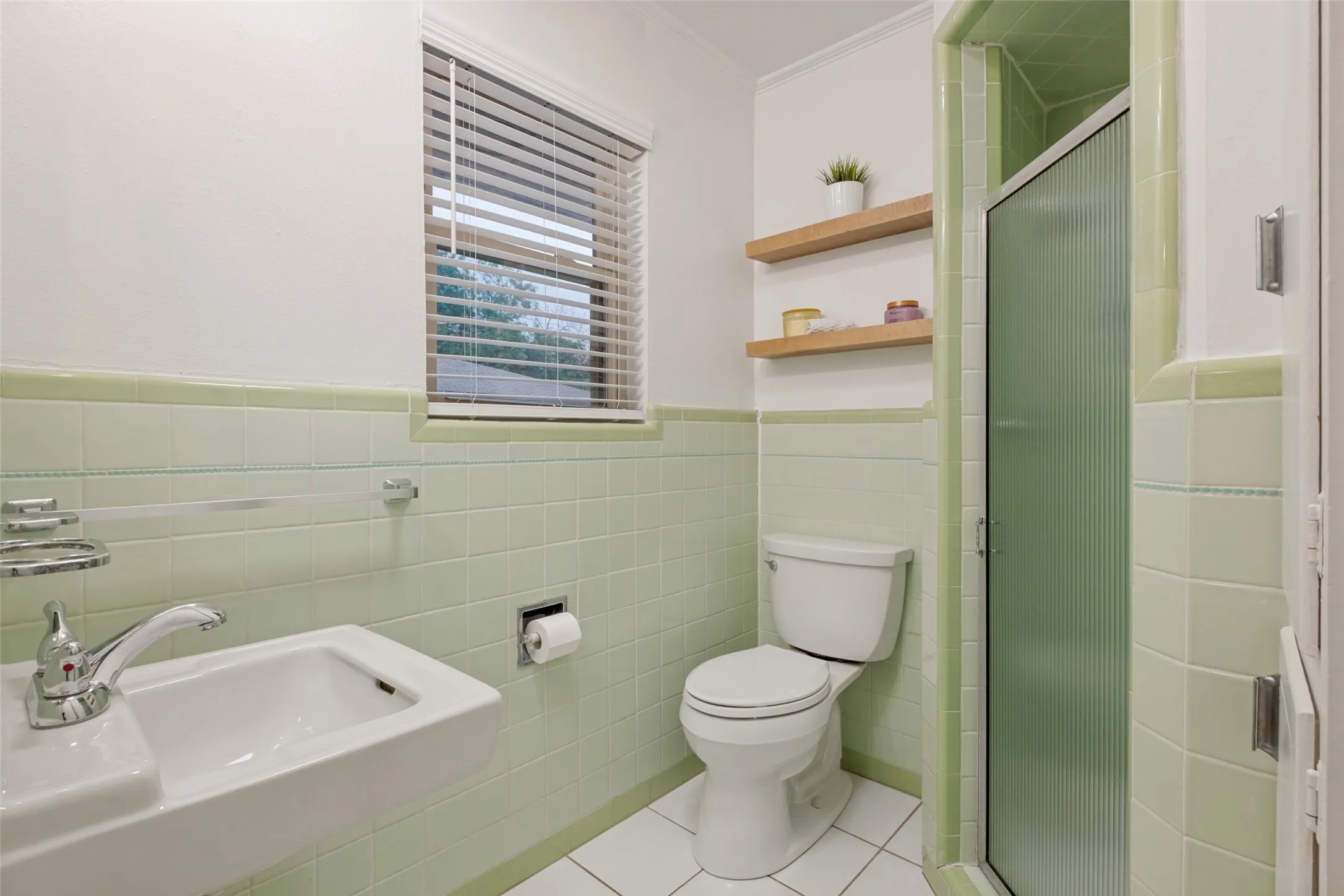 Adorable ensuite bath with shower with built-in cabinets for towels and wooden modern shelving.
