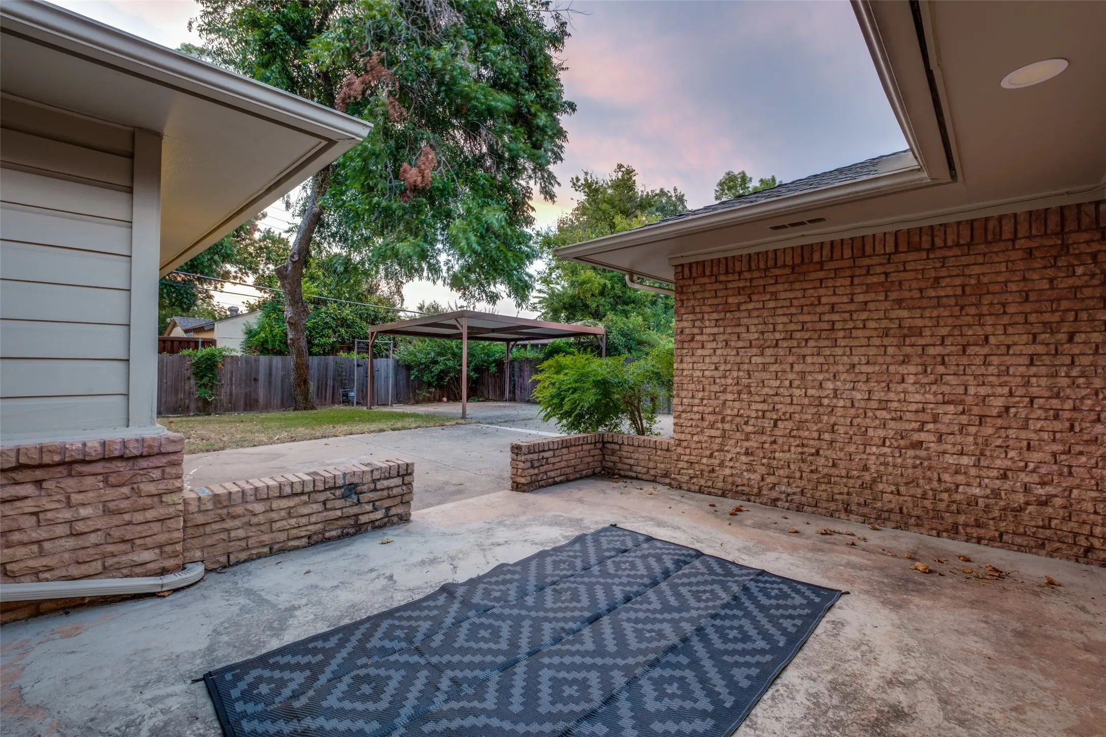 Large Concrete Patio with Drains perfect for entertaining, outdoor dining looking out to the large backyard and driveway.  Carport to the left right could be converted into garage or perfect as is.