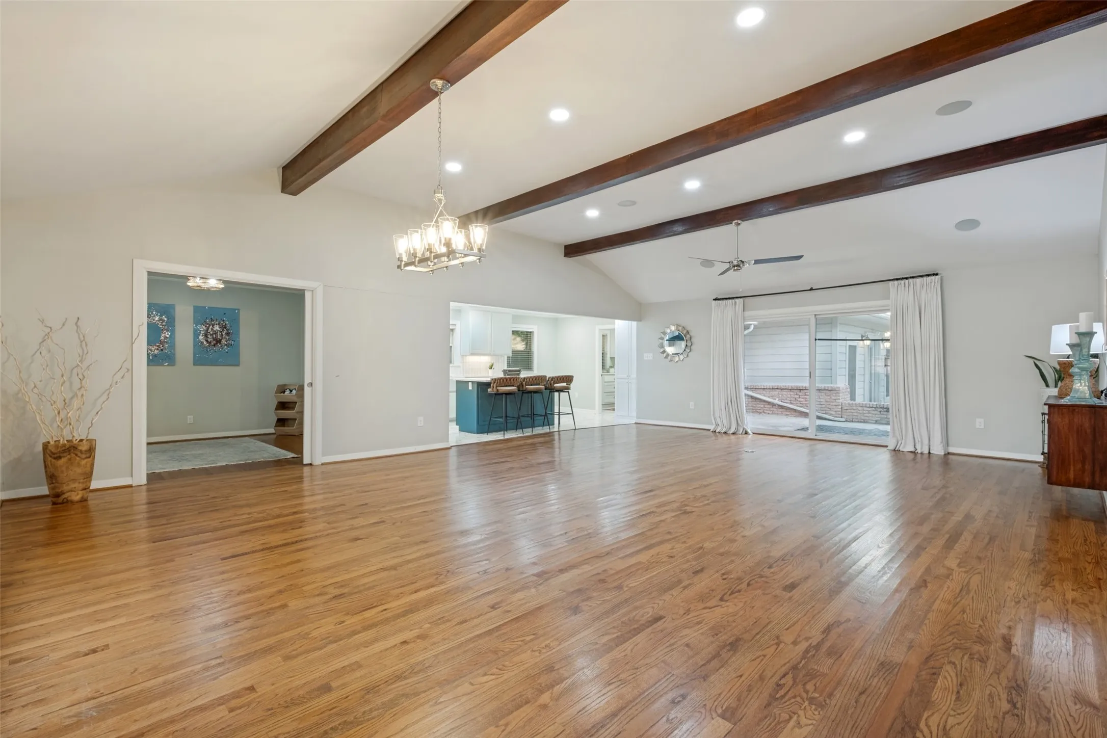 View from Front Door looking into Flex space with pocket sliding door on left and dining area under stunning chandelier.