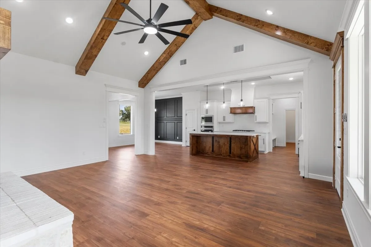 Vaulted ceiling with exposed wood beams and a ceiling fan
