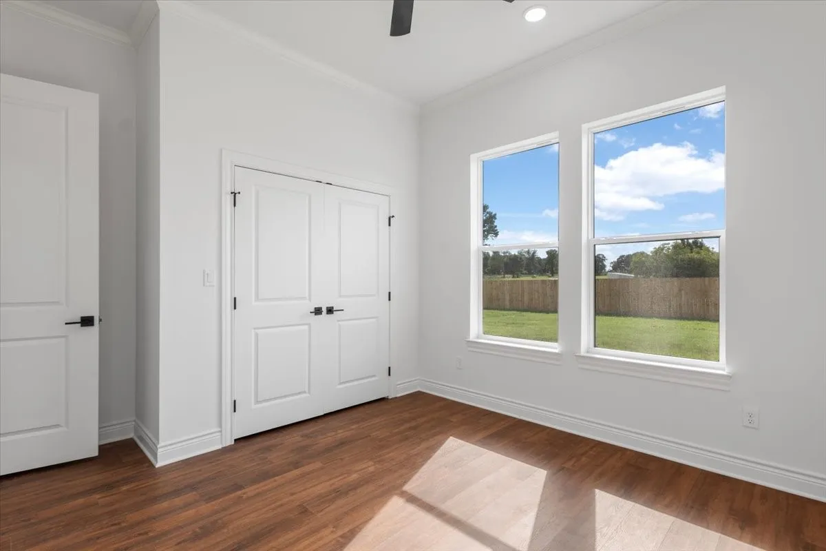 Wood-finish flooring, white walls, white trim, white panel doors with matte black hardware, and two large windows