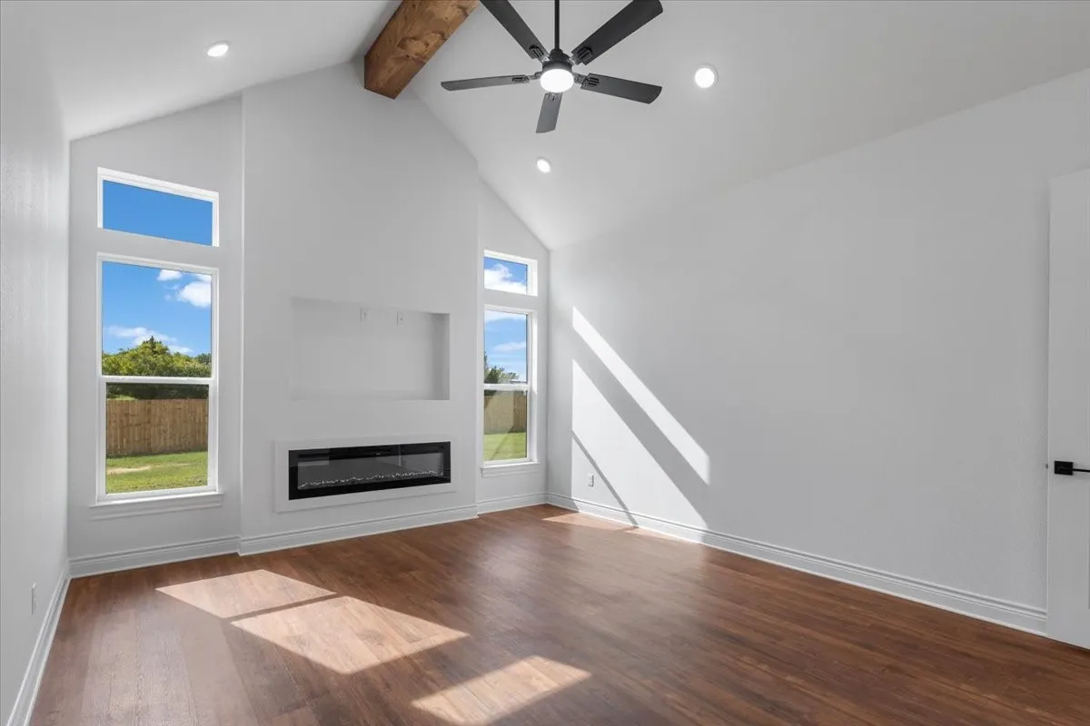 Vaulted ceiling with an exposed wood beam, wood-finish flooring, and recessed lighting