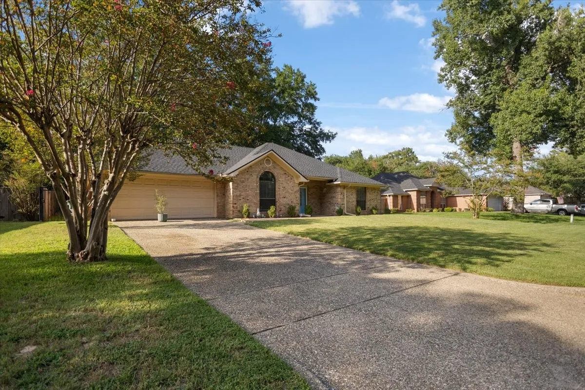 Brick exterior with an arched window accent, attached two-car garage, and a concrete driveway